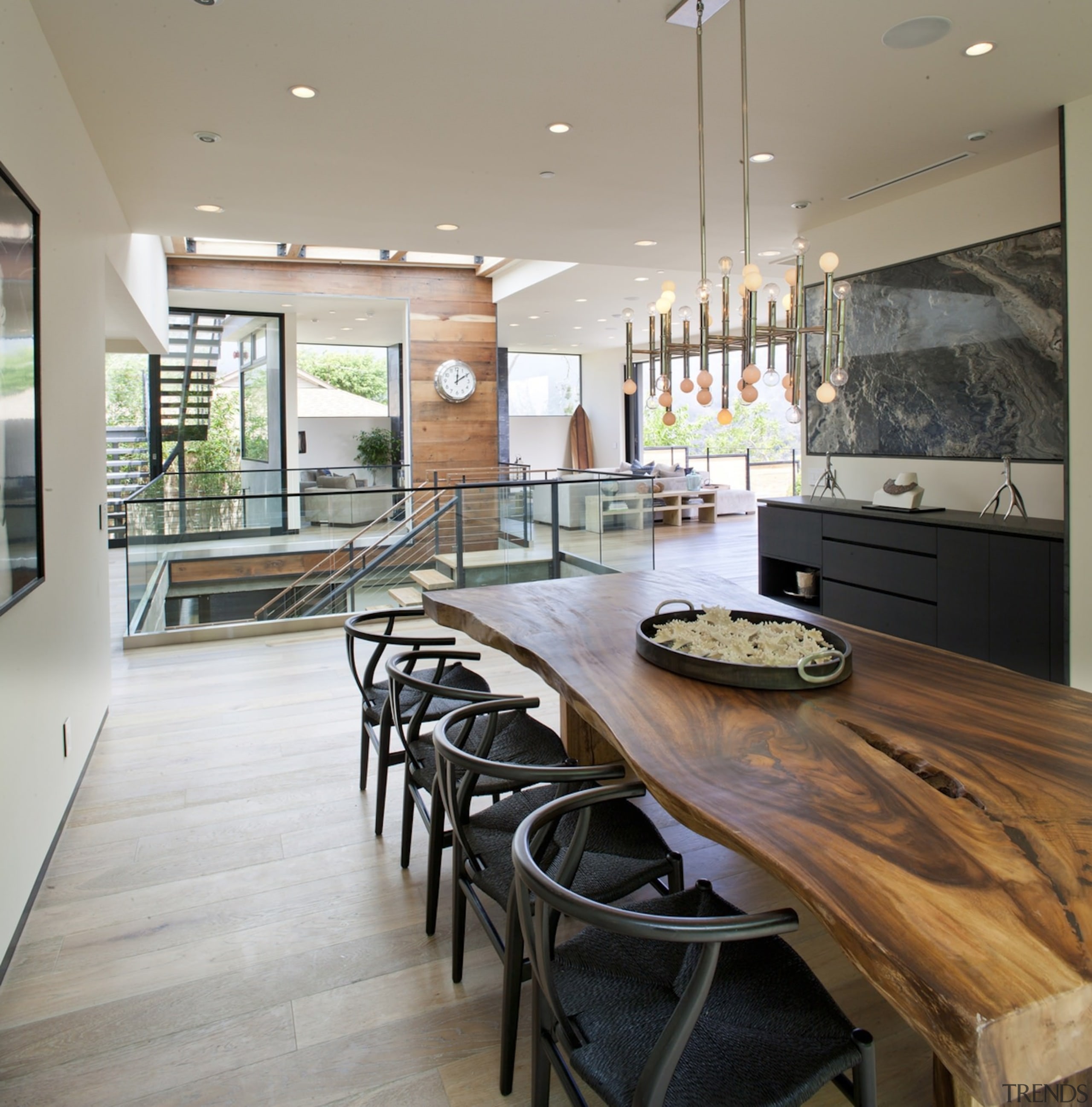 A long dining room features a unique table countertop, floor, flooring, interior design, kitchen, real estate, table, window, wood flooring, gray