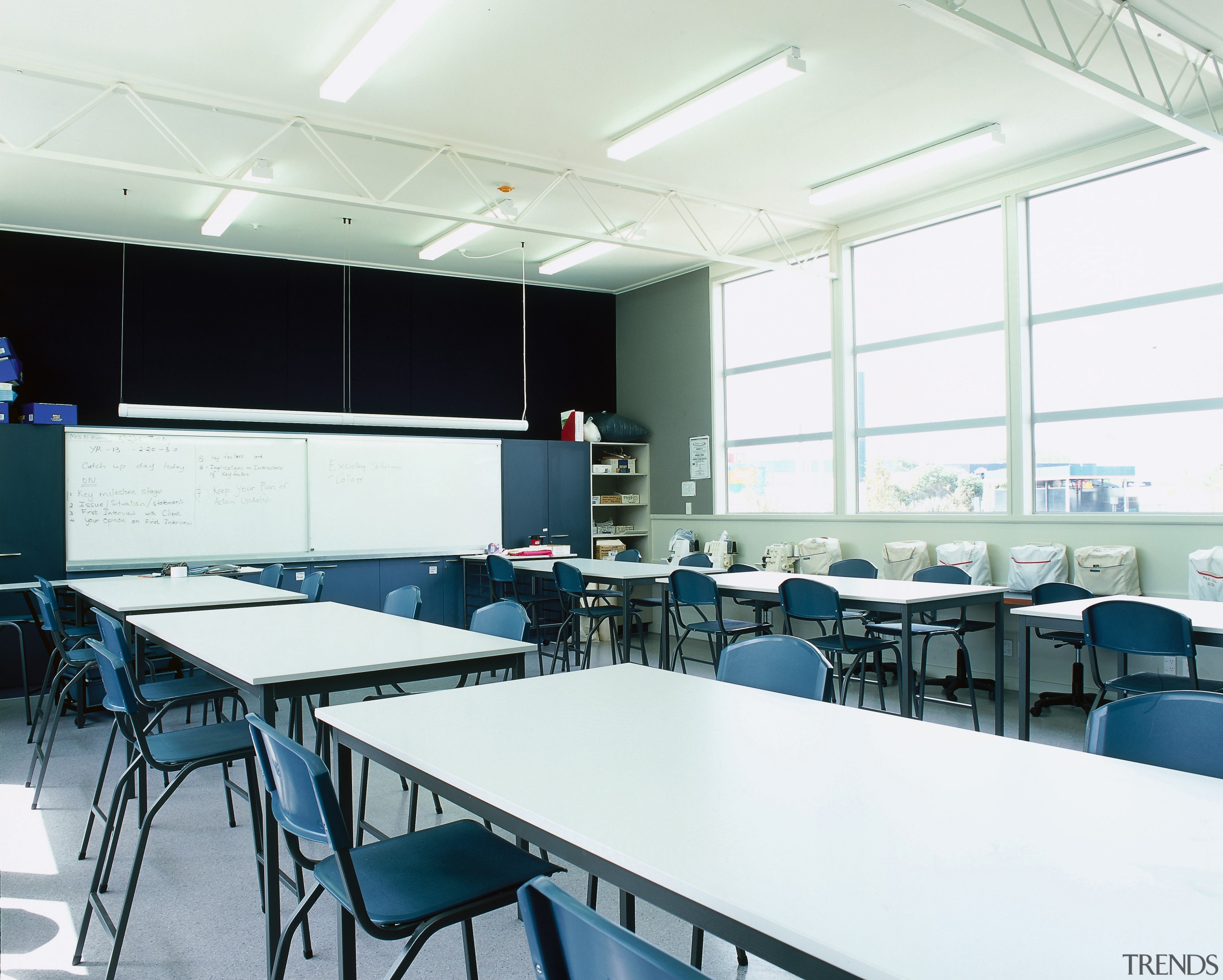 View of a classroom with long tables, chairs, classroom, table, white