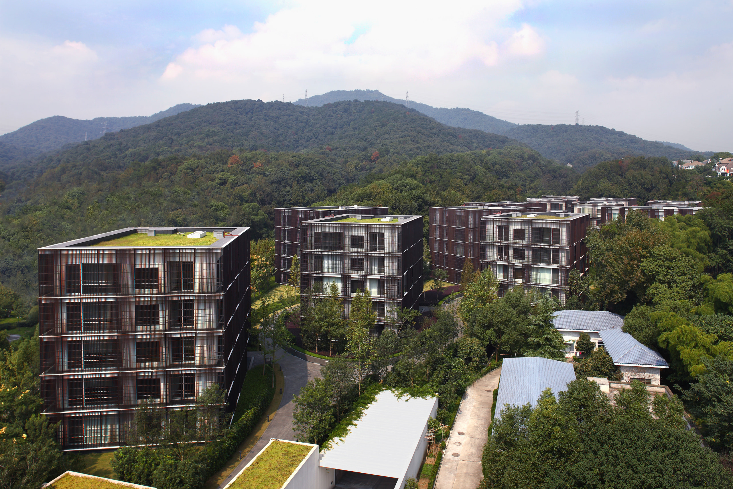 Exterior view of an apartment building which features apartment, bird's eye view, building, city, condominium, estate, hill station, home, house, mixed use, mountain, neighbourhood, property, real estate, residential area, roof, sky, suburb, tower block, tree, white