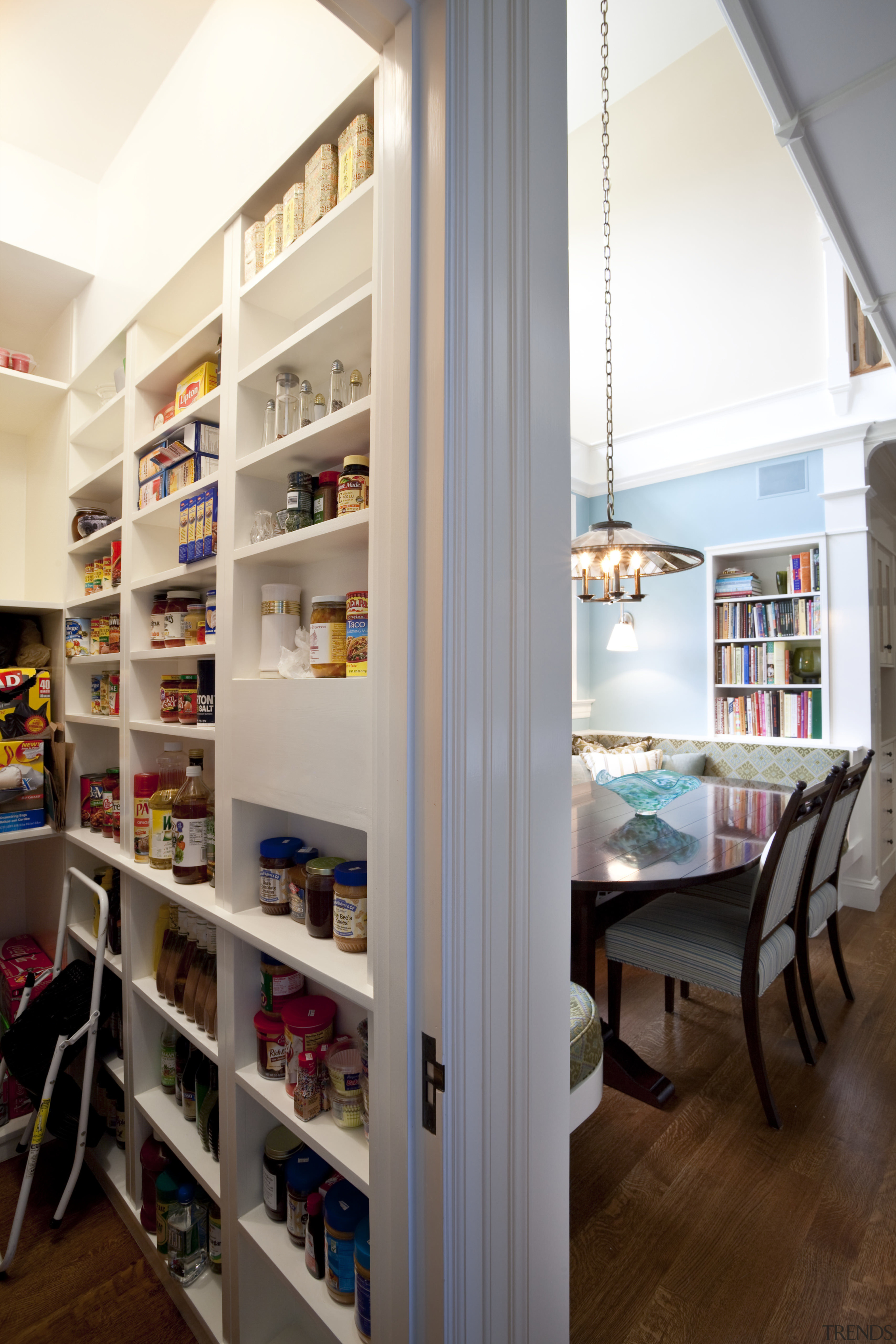 View of kitchen with dark turquoise island, colorful bookcase, interior design, pantry, shelf, shelving, white