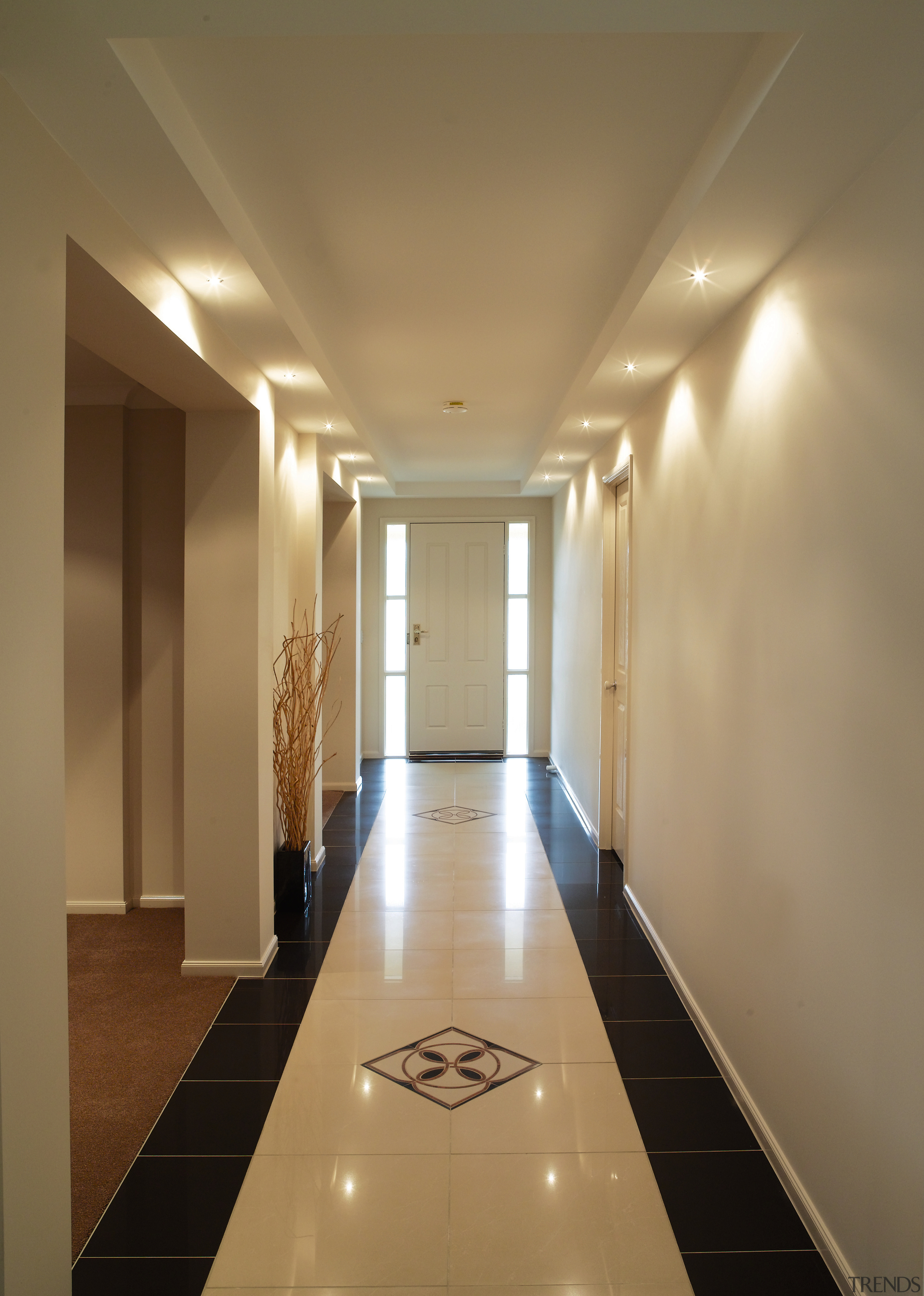 Long hallway with wall sconce luminaries casting pools apartment, architecture, ceiling, daylighting, floor, flooring, hall, interior design, light, lighting, lobby, real estate, wall, brown