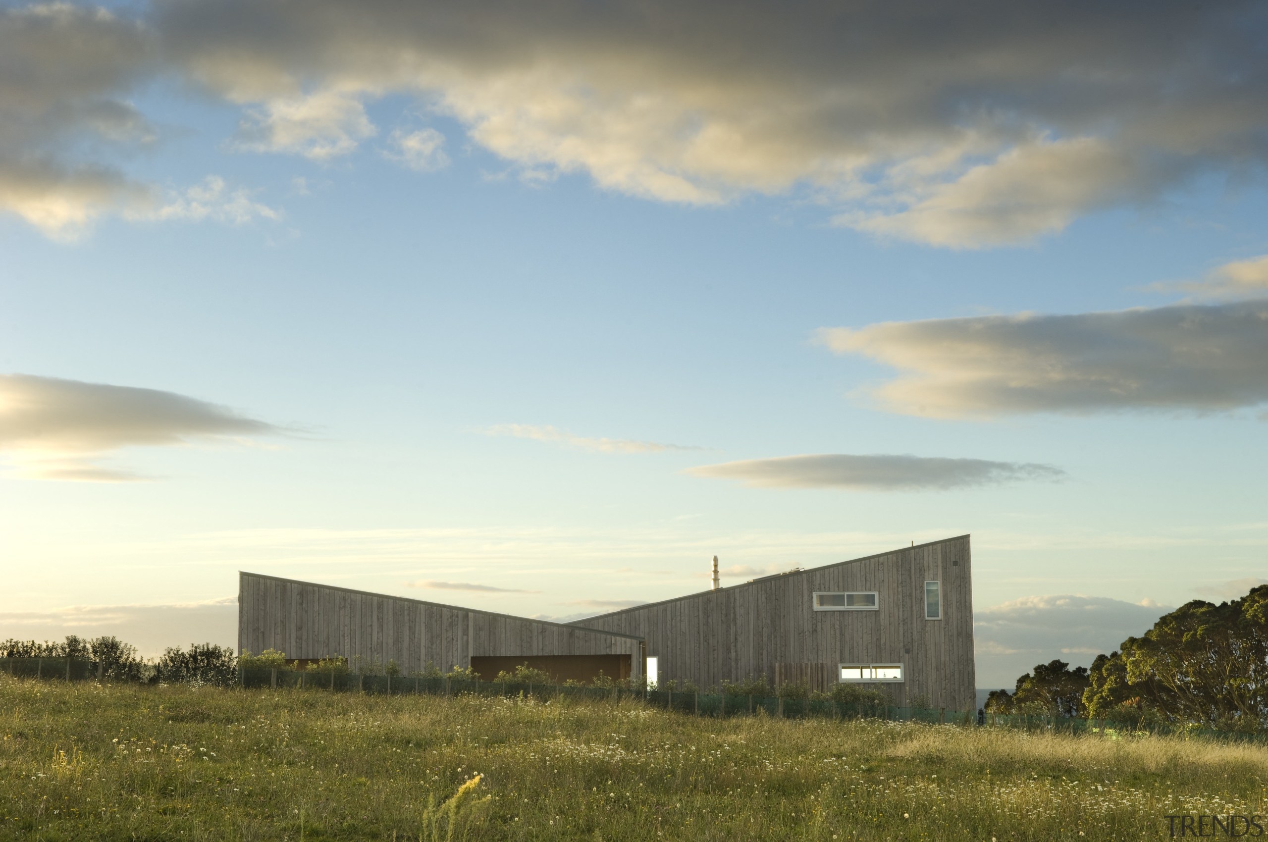 Exterior view of residence which features a monopitched architecture, cloud, dawn, energy, evening, farm, field, grass, grassland, home, horizon, house, landscape, meteorological phenomenon, morning, plain, prairie, real estate, rural area, sky, sunlight, gray