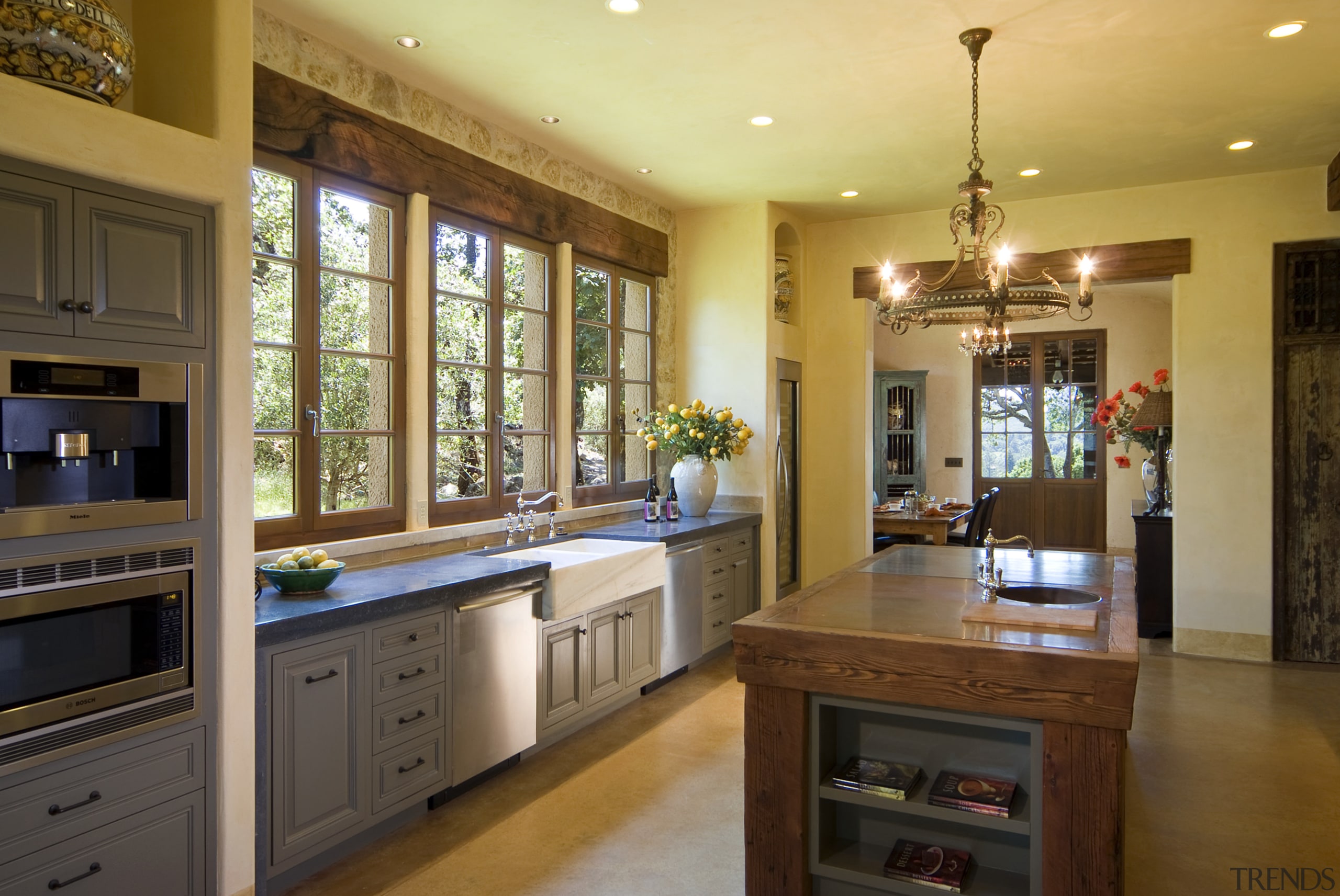 The kitchen area features an island with sink cabinetry, countertop, interior design, kitchen, real estate, room, brown