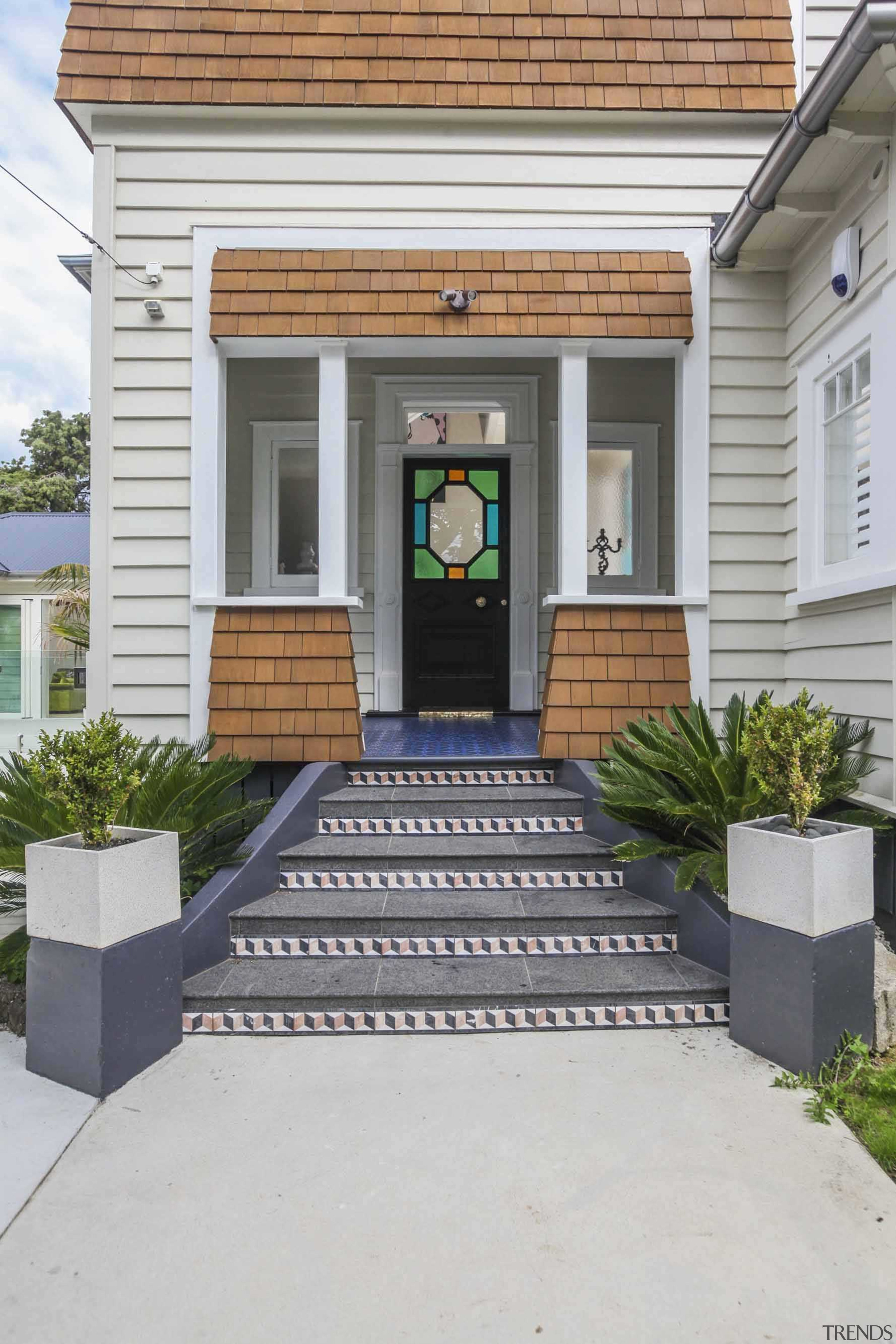 The front entrance features a stained glass window door, facade, home, house, porch, real estate, siding, walkway, gray