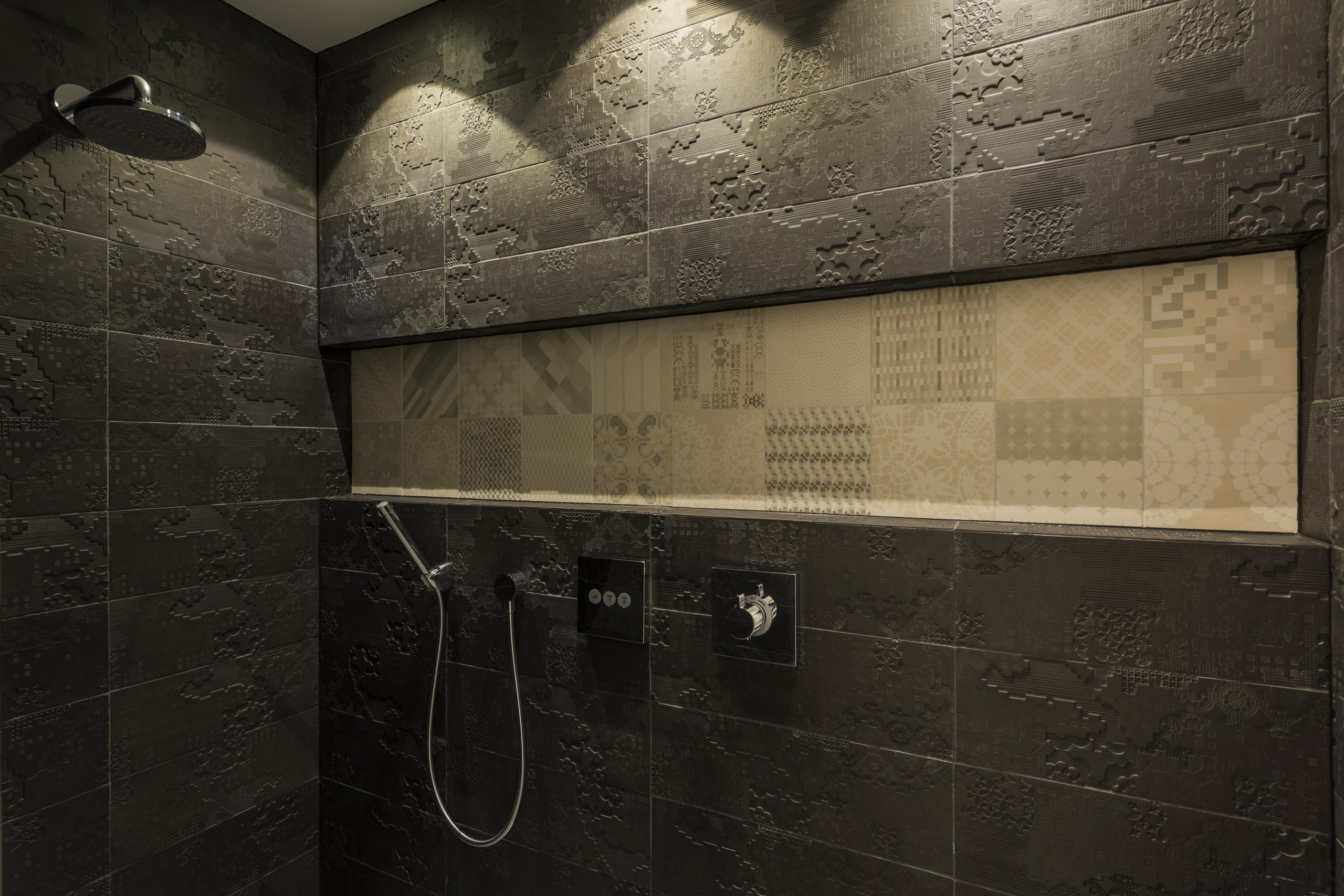 The custom Italian porcelain tile inset in this architecture, bathroom, darkness, floor, flooring, interior design, light, public toilet, reflection, room, texture, tile, wall, black