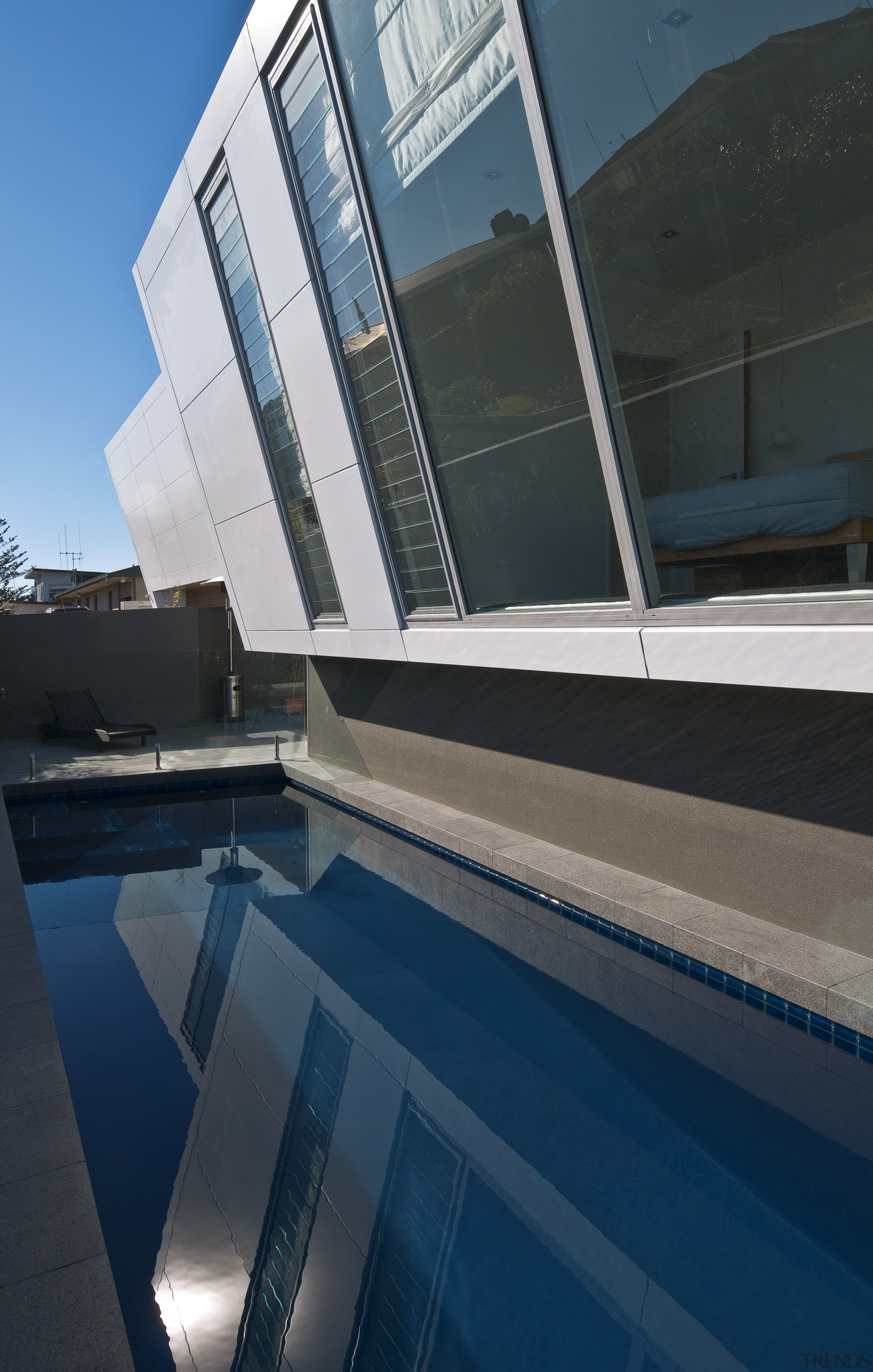 Image of a residential minimalist pool constructed by architecture, building, daylighting, daytime, facade, glass, house, property, reflection, sky, swimming pool, water, window, black