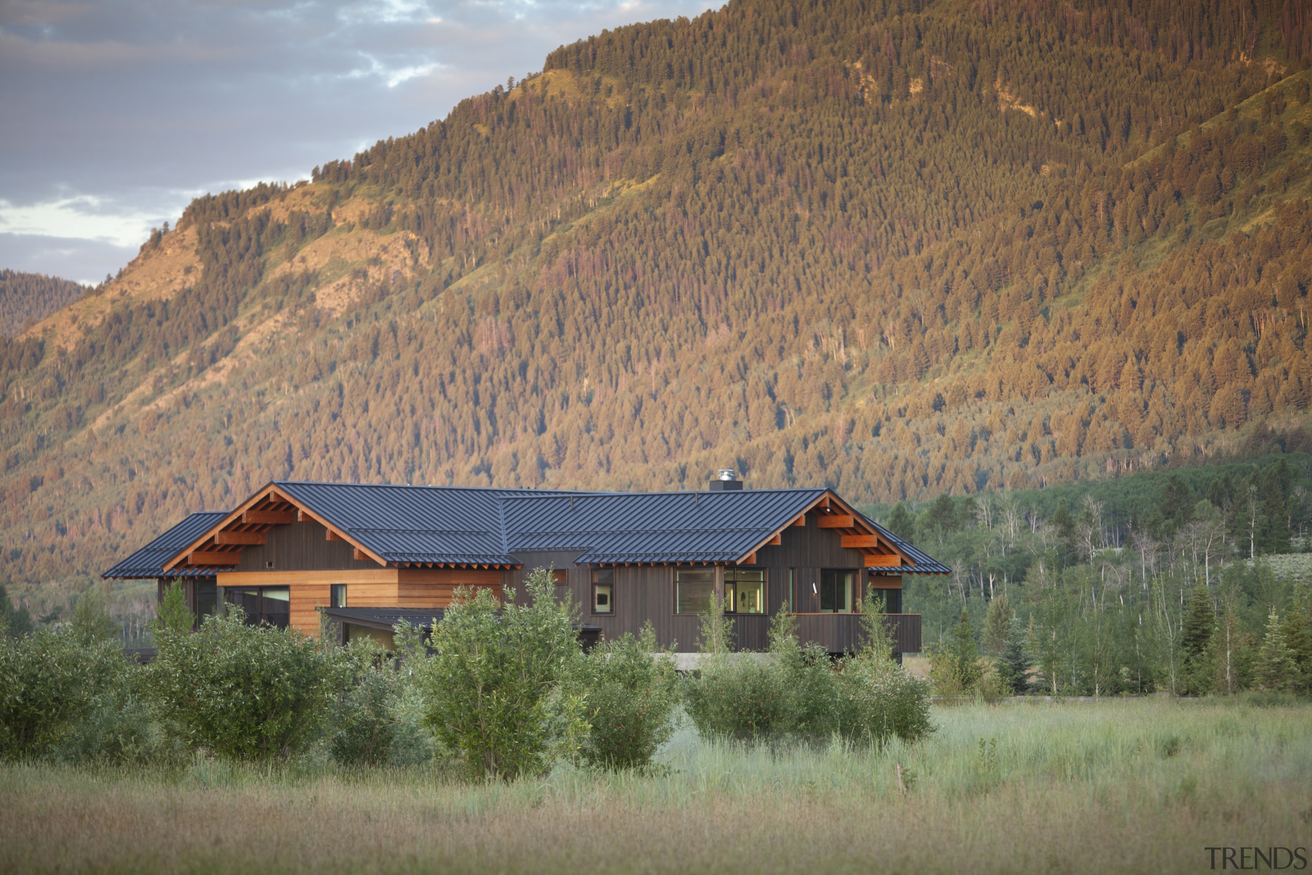 This rustic-looking mountain home by architect Stephen Dynia biome, cloud, cottage, farm, field, grassland, highland, hill, home, house, hut, landscape, log cabin, morning, mountain, mountain range, mountainous landforms, national park, nature, real estate, roof, rural area, sky, sunlight, tree, wilderness, brown