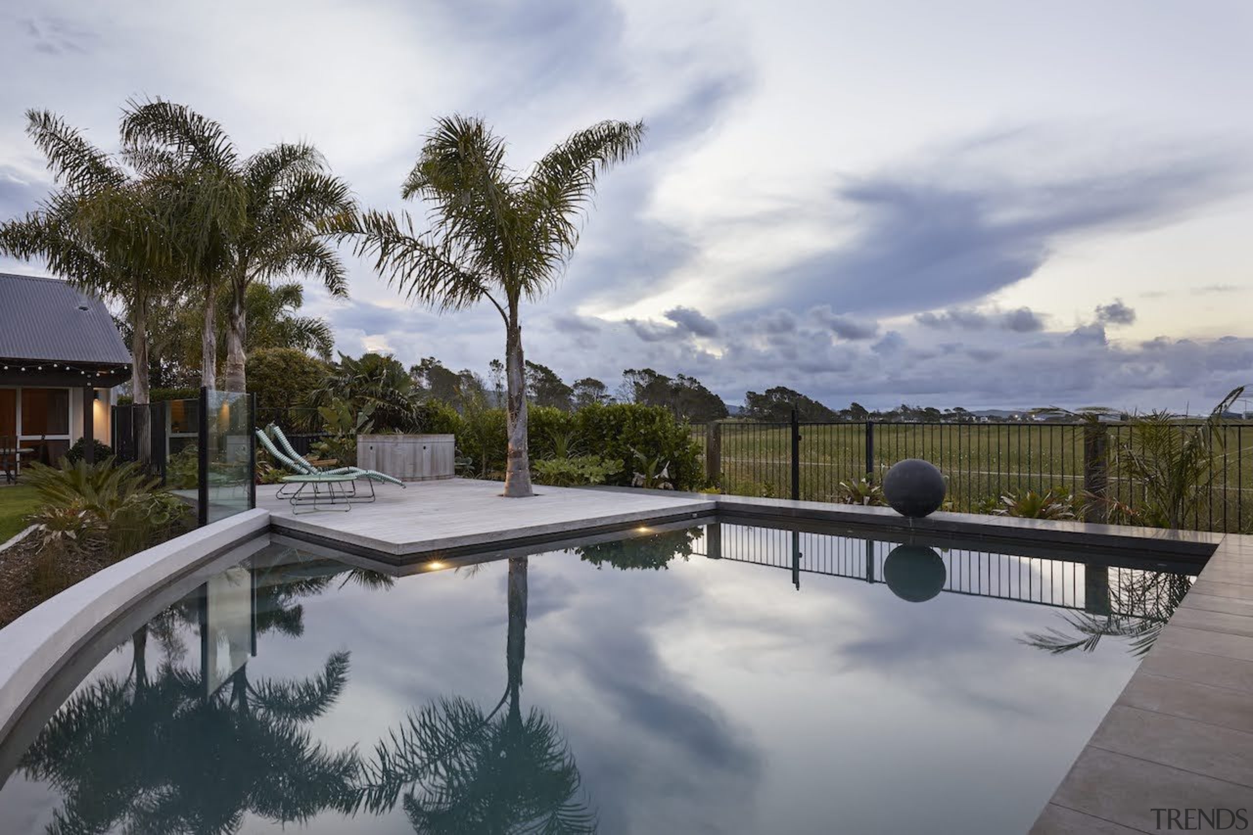 The corner swimming pool reflects the sky, palms 