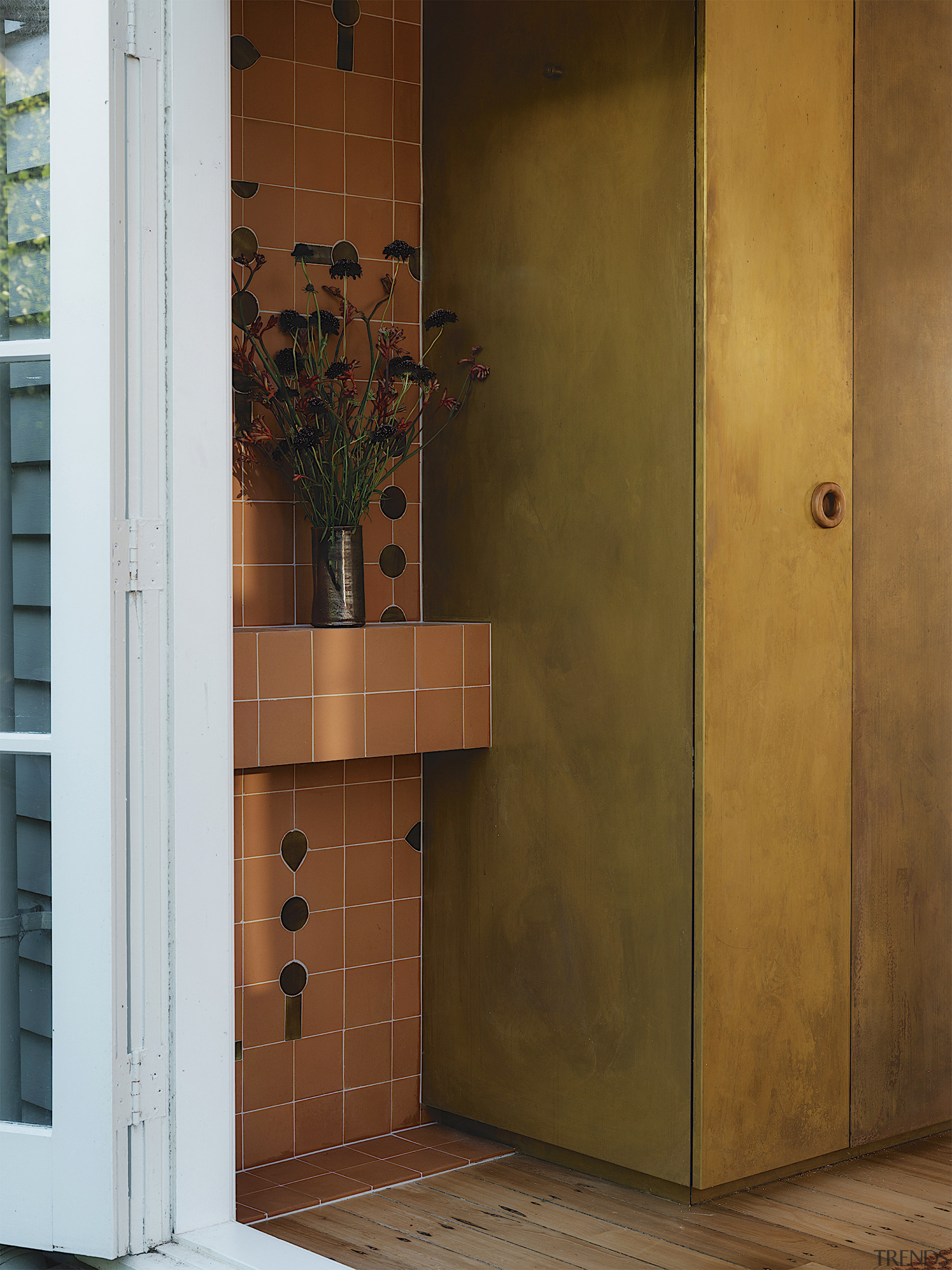 Terracotta tile meets brass cabinetry finish in a 