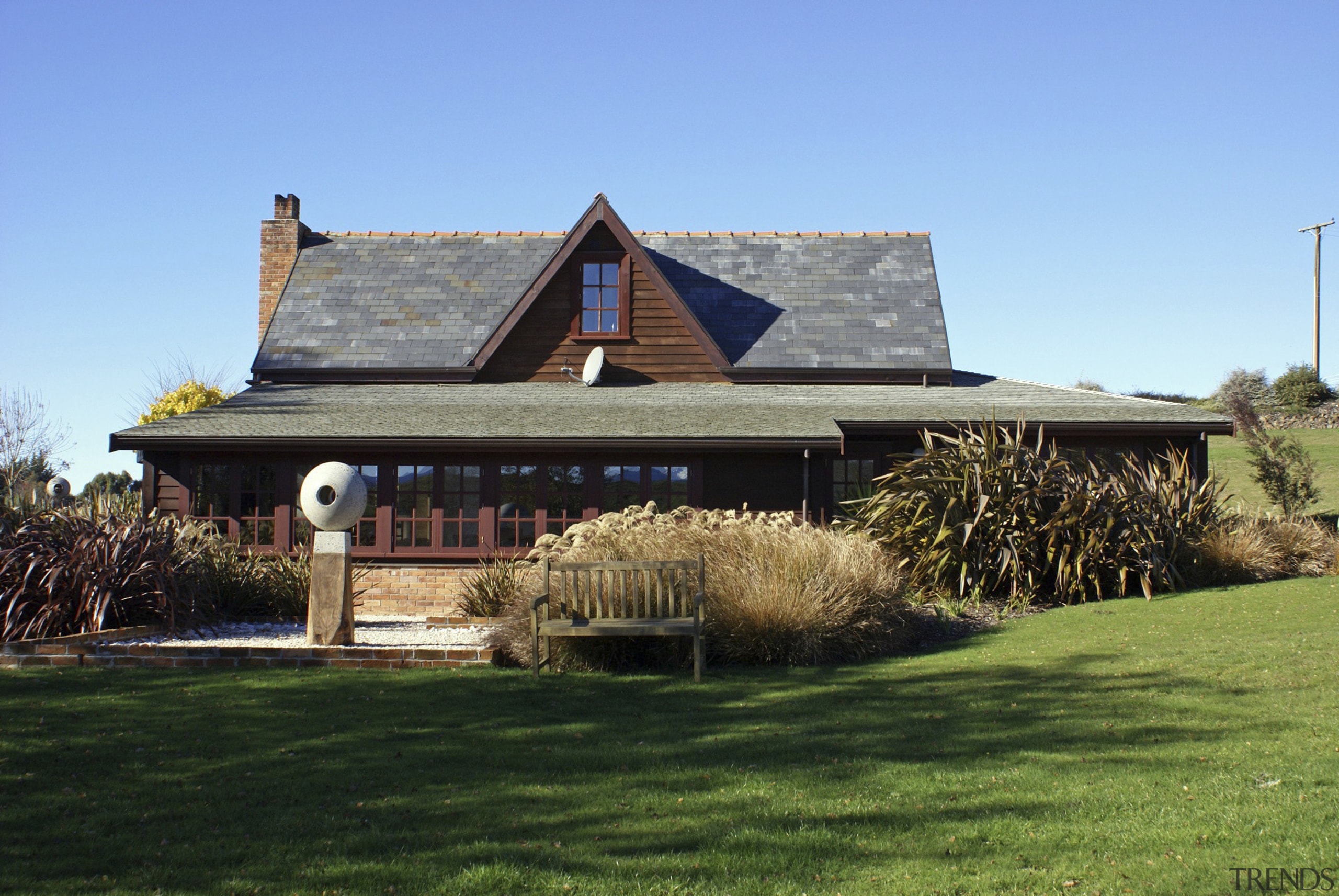 Exterior view with bush outside. - Exterior view cottage, estate, farmhouse, grass, home, house, landscape, outdoor structure, property, real estate, roof, sky, teal