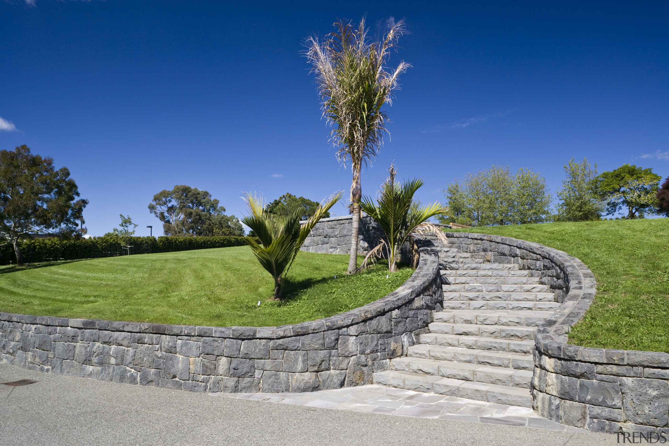 Image of stone walls which have been built estate, garden, grass, landscape, landscaping, lawn, path, sky, stone wall, tree, walkway, wall, gray, blue