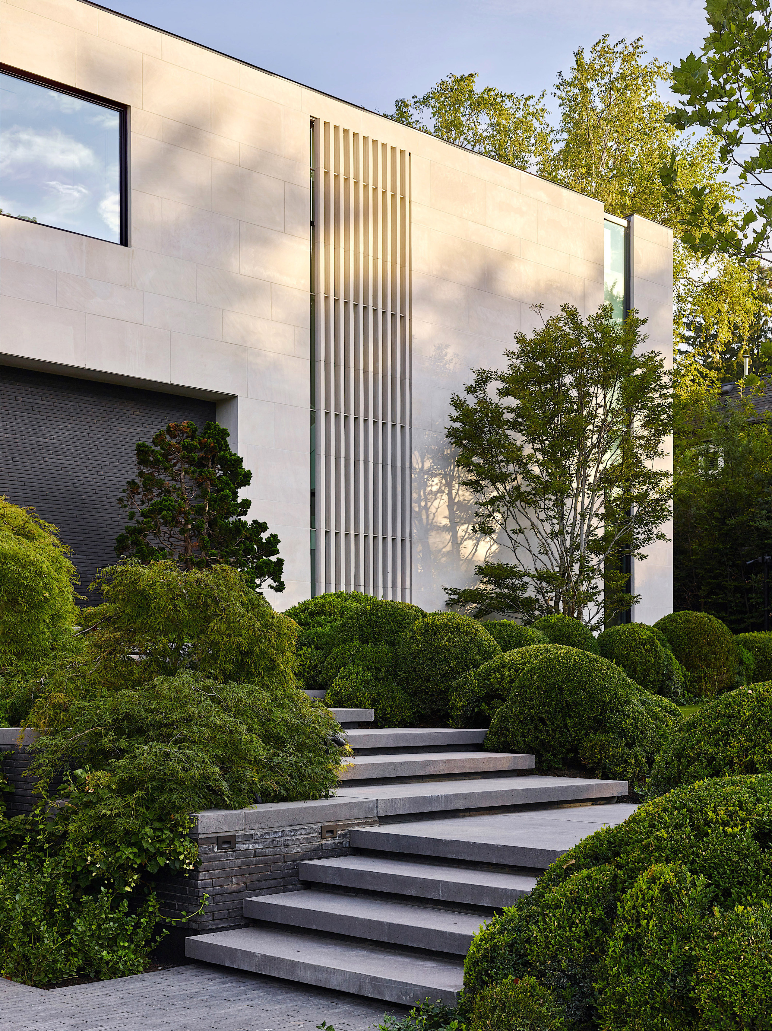 The home's stepped approach is edged in shrubbery. 