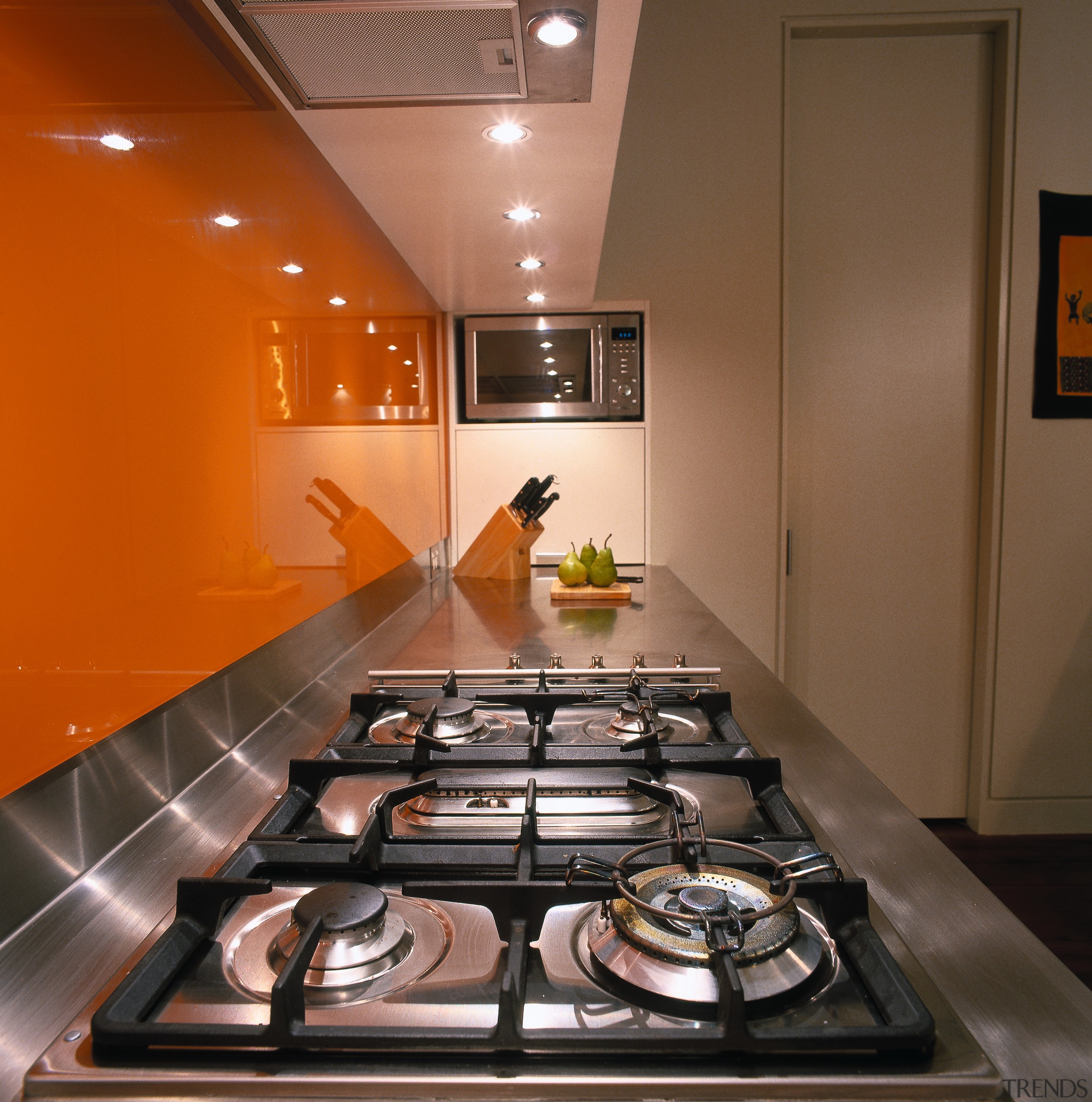A view of a kitchen, orange glass splashback, ceiling, countertop, interior design, room, table, brown