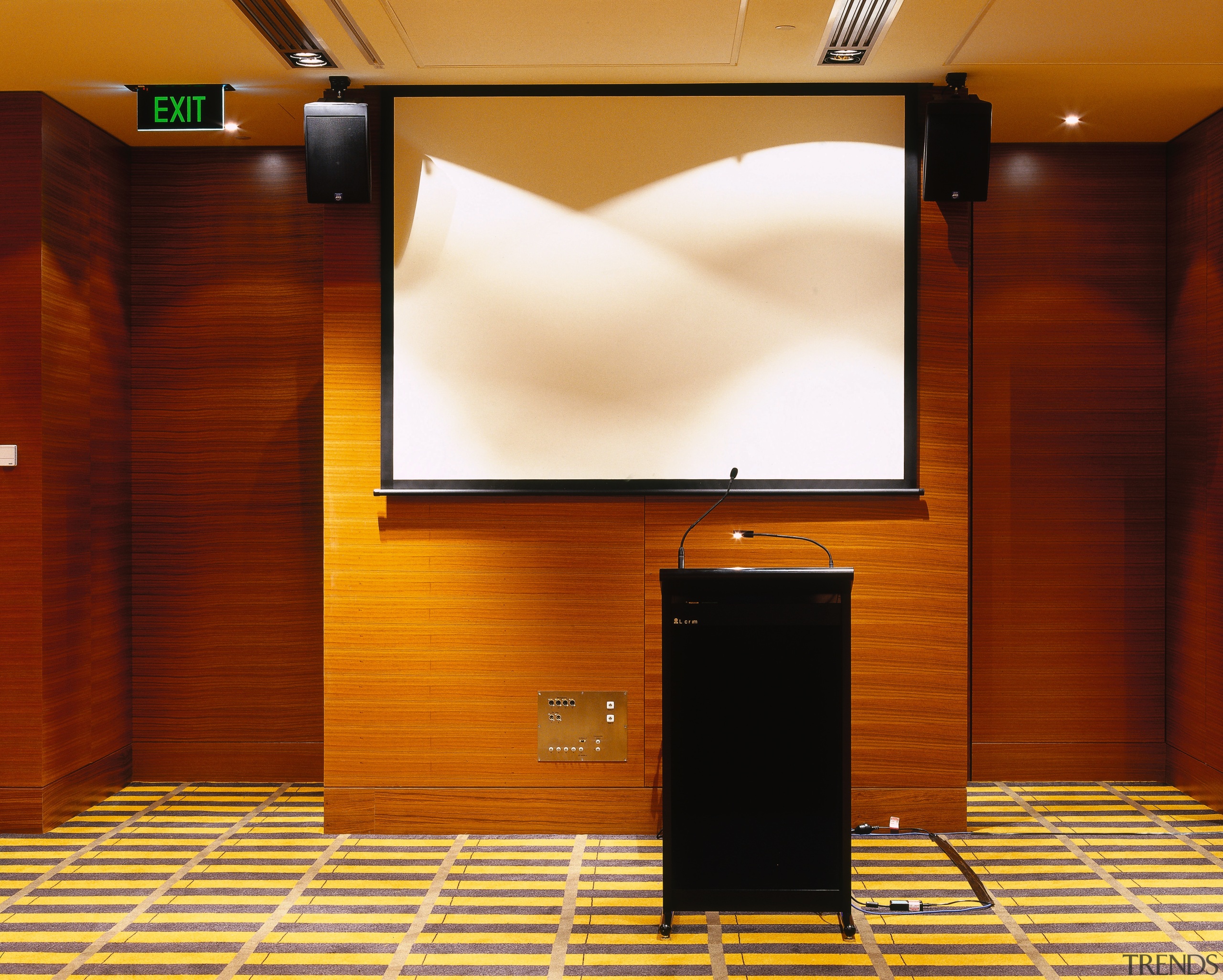 Function room with black podium, white screen and display device, flooring, furniture, interior design, projection screen, room, brown