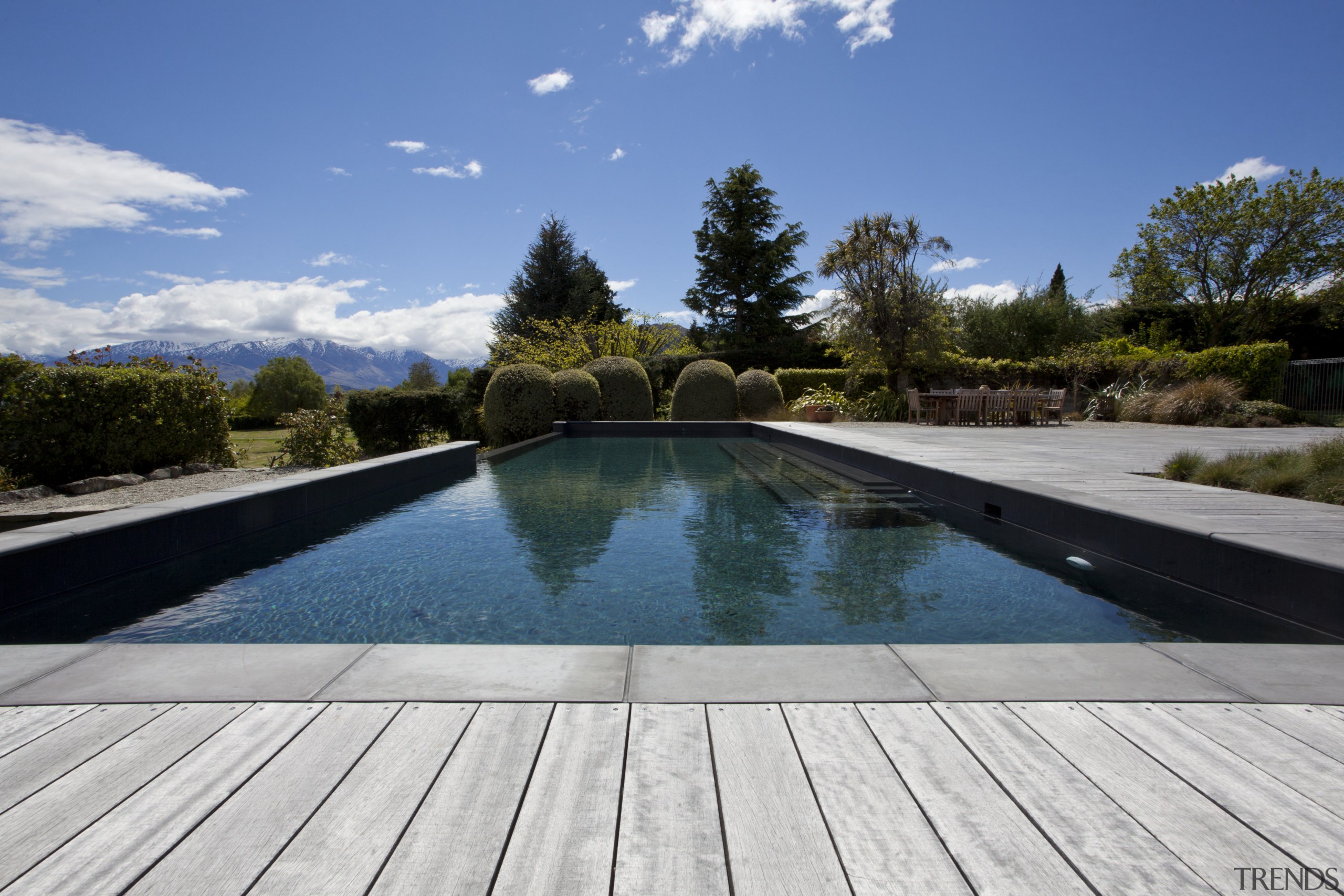 View of pool and landscaping. - View of estate, landscape, plant, property, real estate, reflection, sky, swimming pool, tree, water, gray, teal