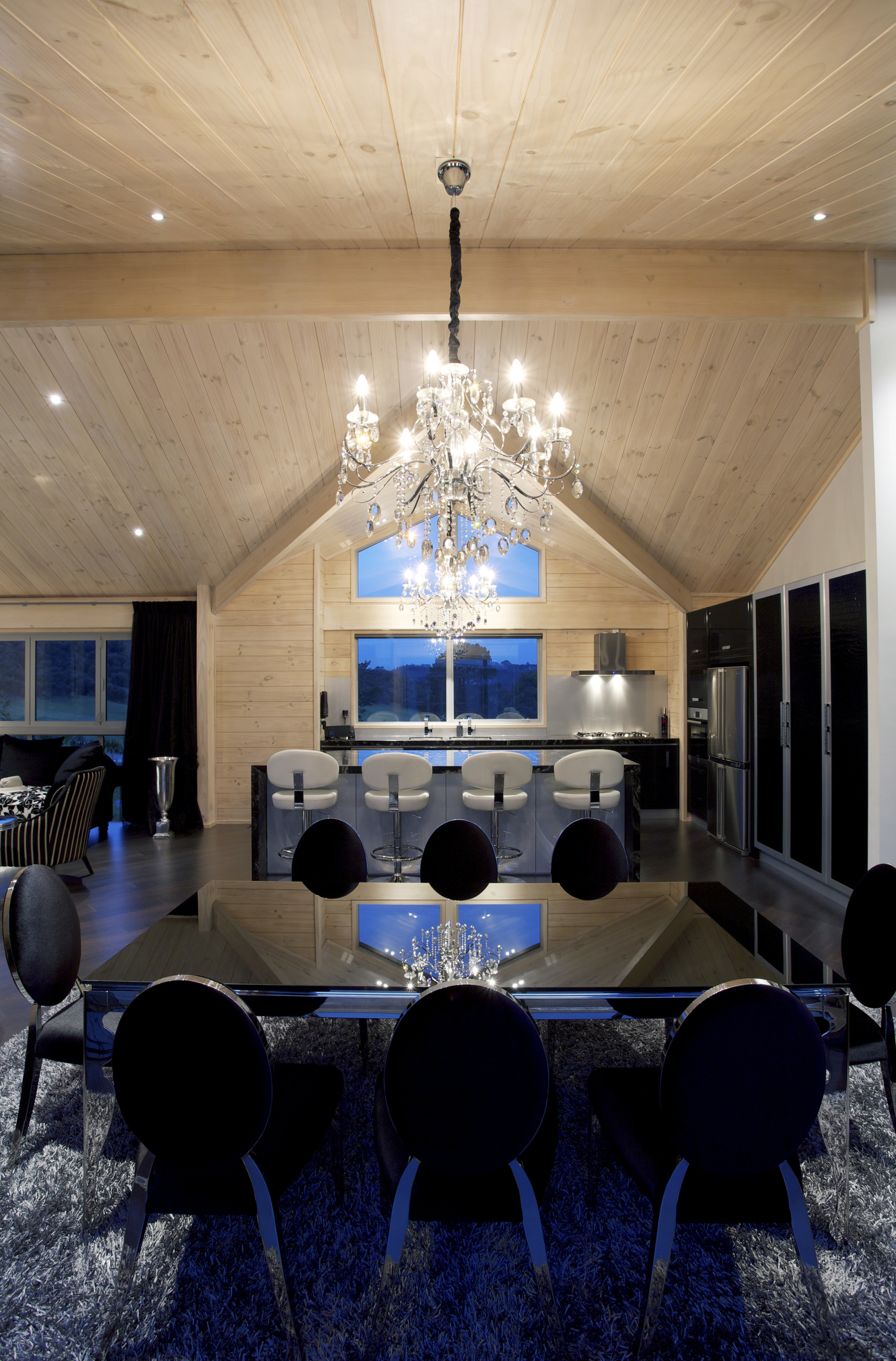 Dramatic black and white furnishings contrast the washed architecture, ceiling, chandelier, dining room, furniture, home, house, interior design, light fixture, lighting, lobby, room, table, black