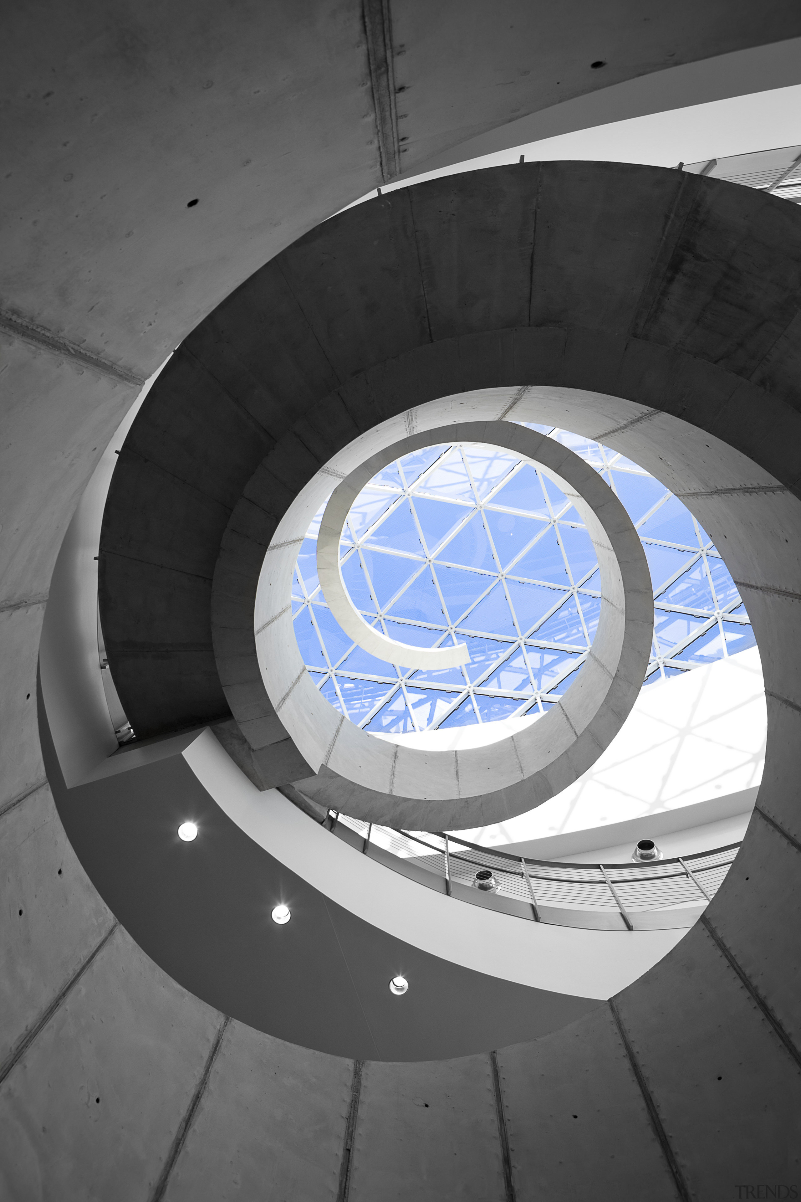 A dramatic spiral concrete staircase is a feature angle, architecture, circle, daylighting, daytime, light, line, product design, sky, spiral, structure, wheel, black, gray