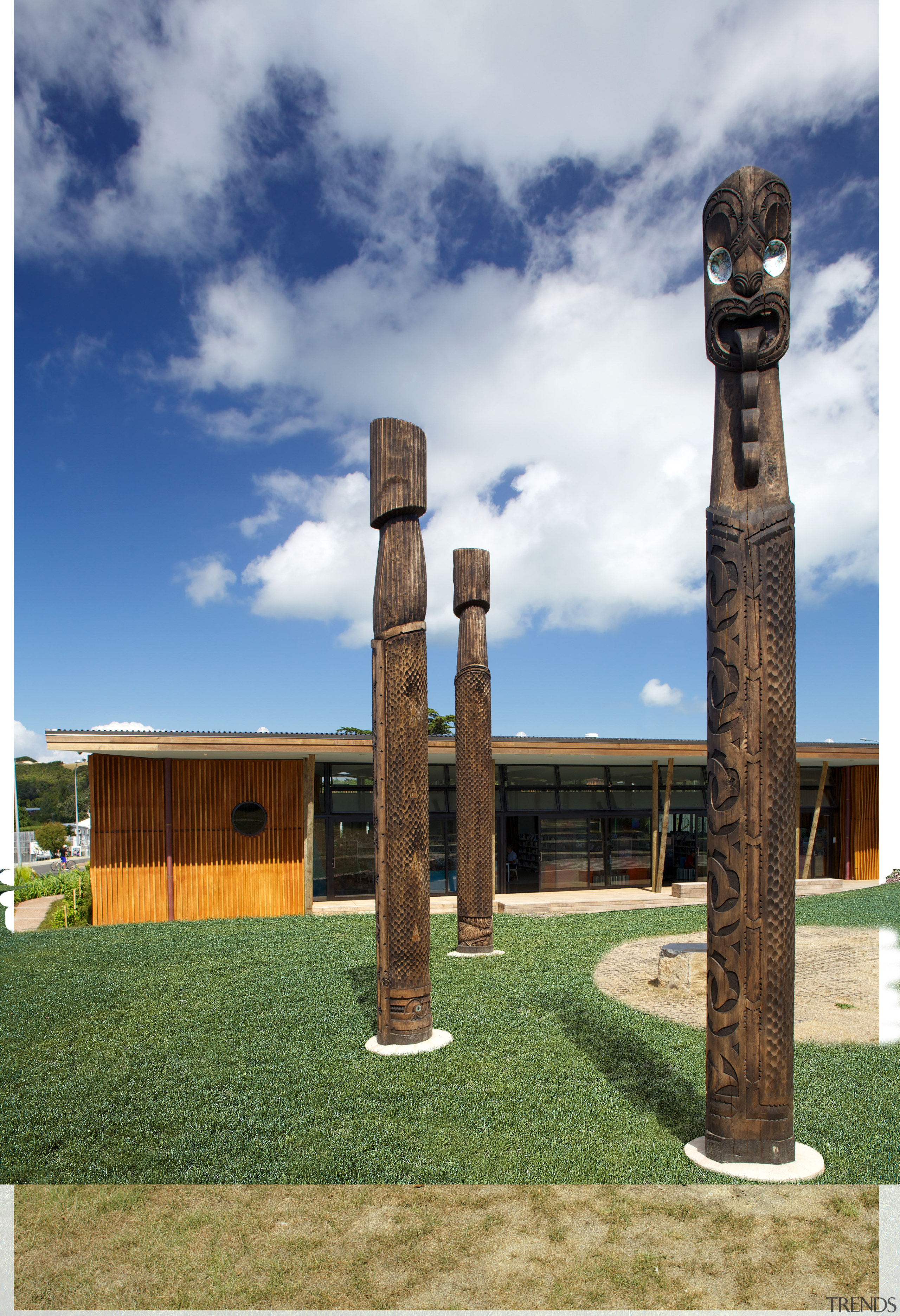 Carved timber battens wrap around the exterior of cloud, column, grass, sky