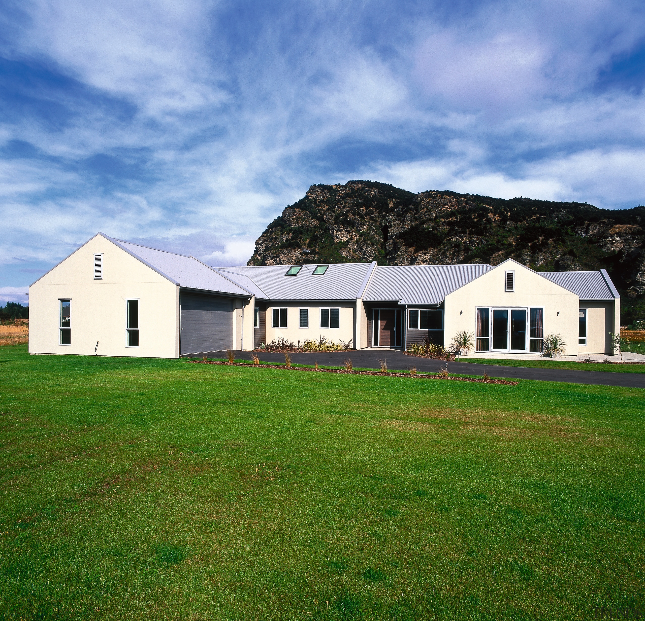 Exterior view of entire cream clad house with architecture, barn, cloud, cottage, estate, facade, farm, farmhouse, field, grass, grassland, home, house, land lot, landscape, lawn, pasture, property, real estate, residential area, roof, rural area, siding, sky, teal, green