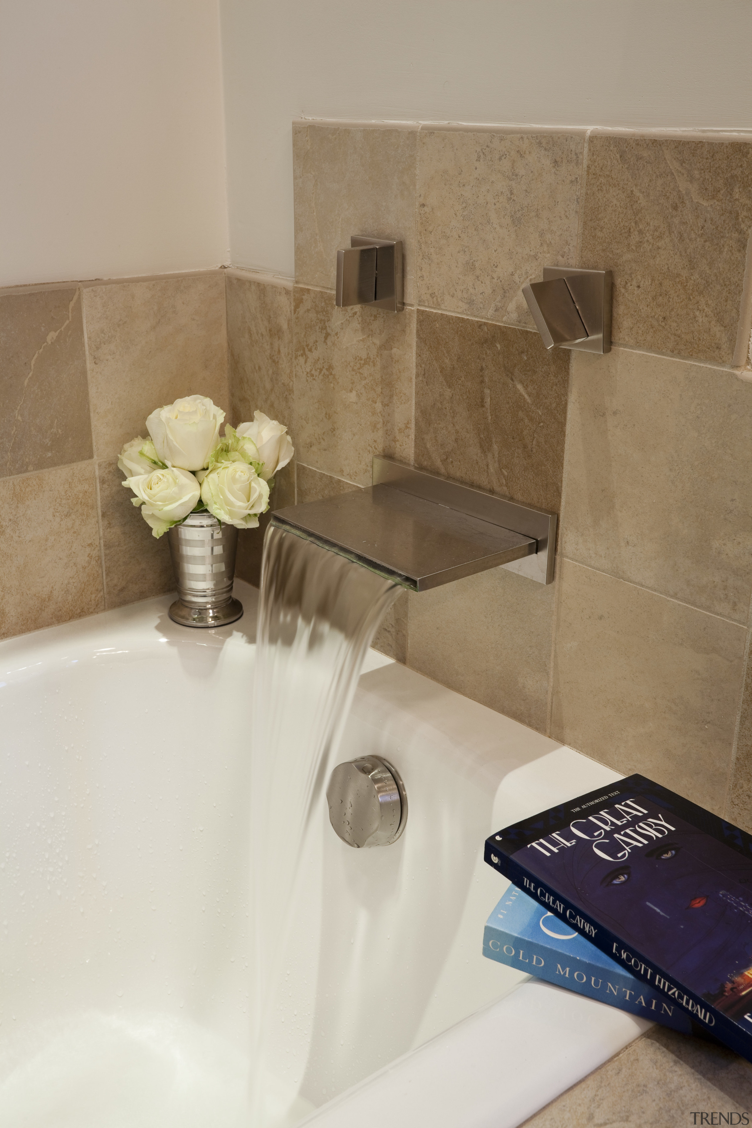 A gentle waterfall fills the tub, which is bathroom, floor, flooring, plumbing fixture, room, sink, tap, tile, gray, brown