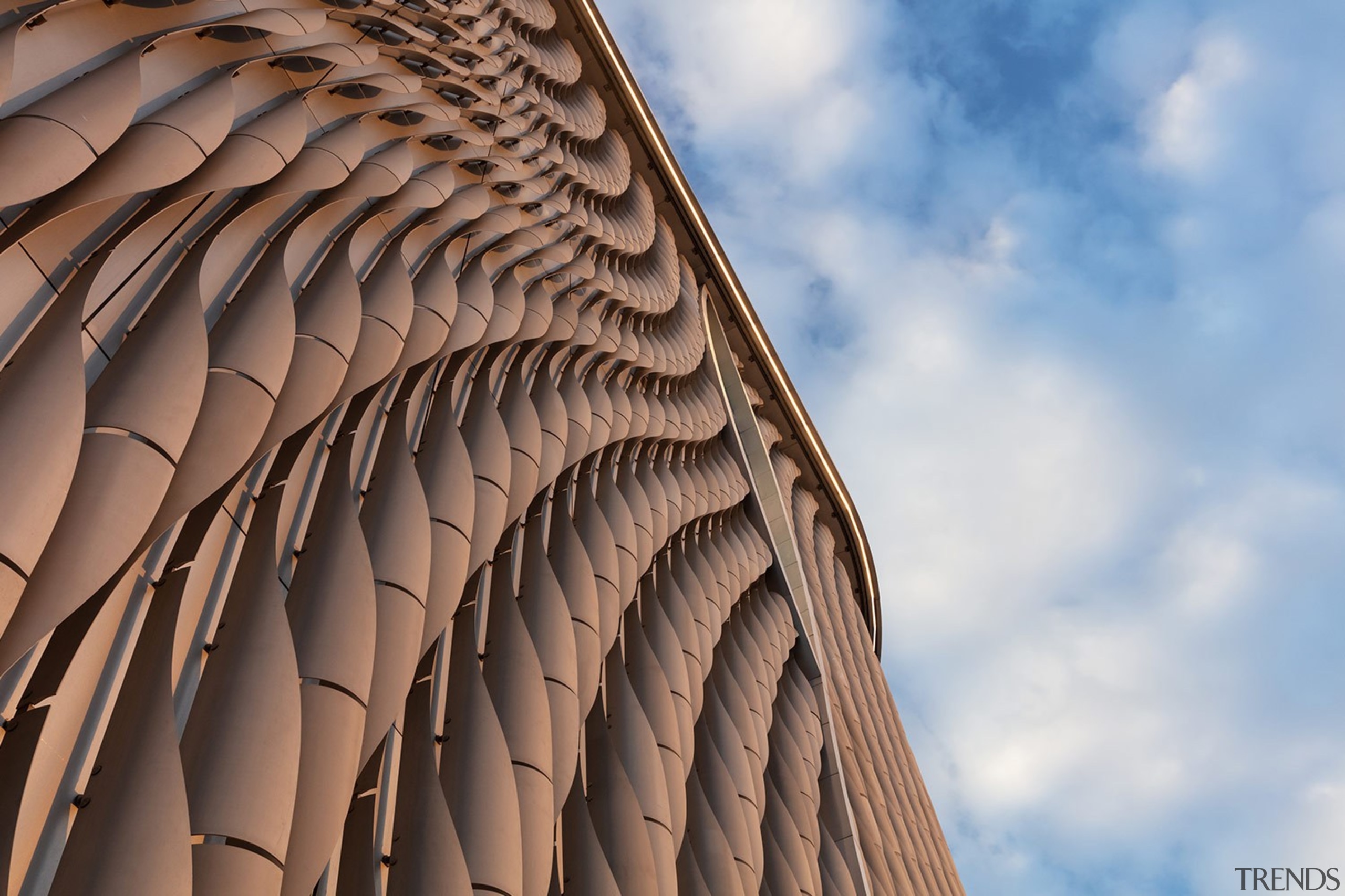 The curvature of the facade form represents the architecture, blue, building, cloud, daytime, design, facade, landmark, line, pattern, sky, symmetry, brown, gray