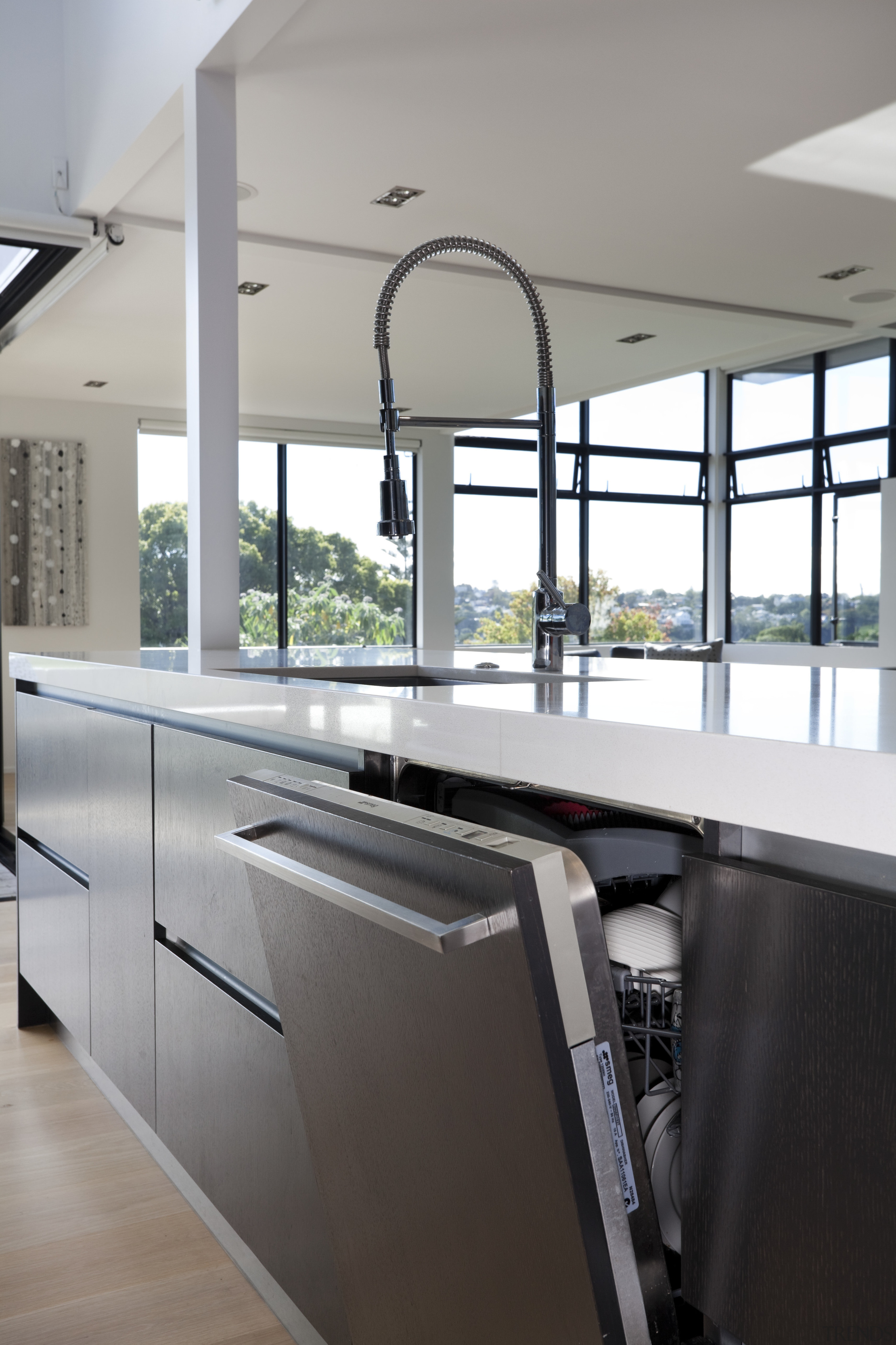 View of open dishwasher with dark cupboards and architecture, countertop, floor, glass, handrail, interior design, kitchen, gray