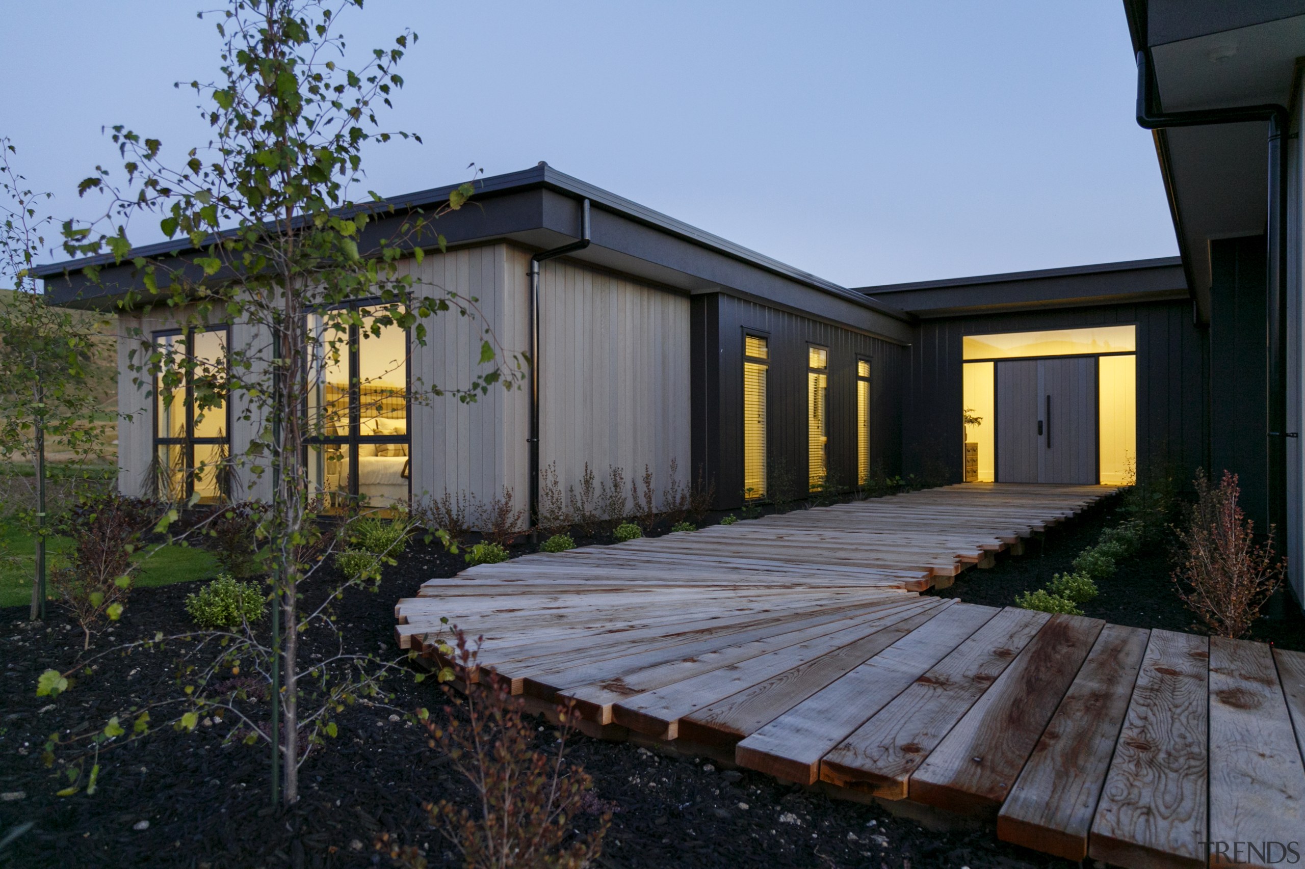 ​​​​​​​A timber boardwalk leads to a solid front architecture, backyard, building, cottage, estate, facade, home, house, landscape, property, real estate, residential area, roof, shed, siding, tree, window, wood, yard, black