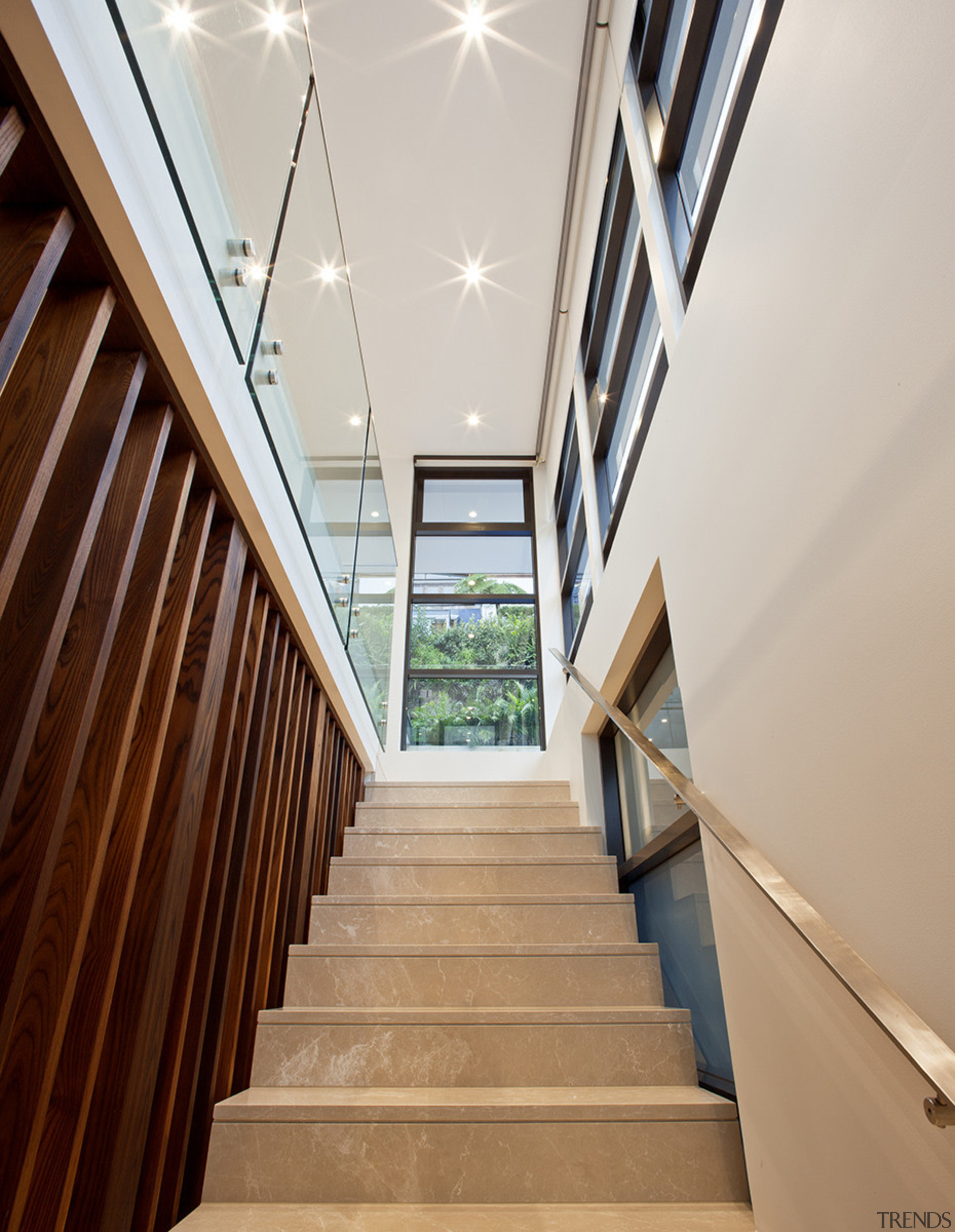 In this home by designer James Cooper, the apartment, architecture, ceiling, daylighting, estate, floor, handrail, house, interior design, lobby, property, real estate, stairs, window, wood, gray