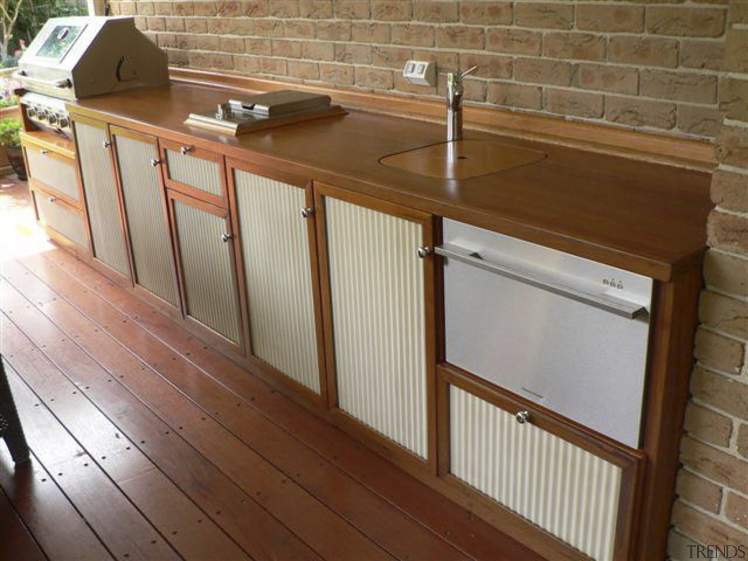 View of an outdoor area which features outdoor cabinetry, countertop, floor, flooring, furniture, handrail, hardwood, wood, wood stain, brown, gray