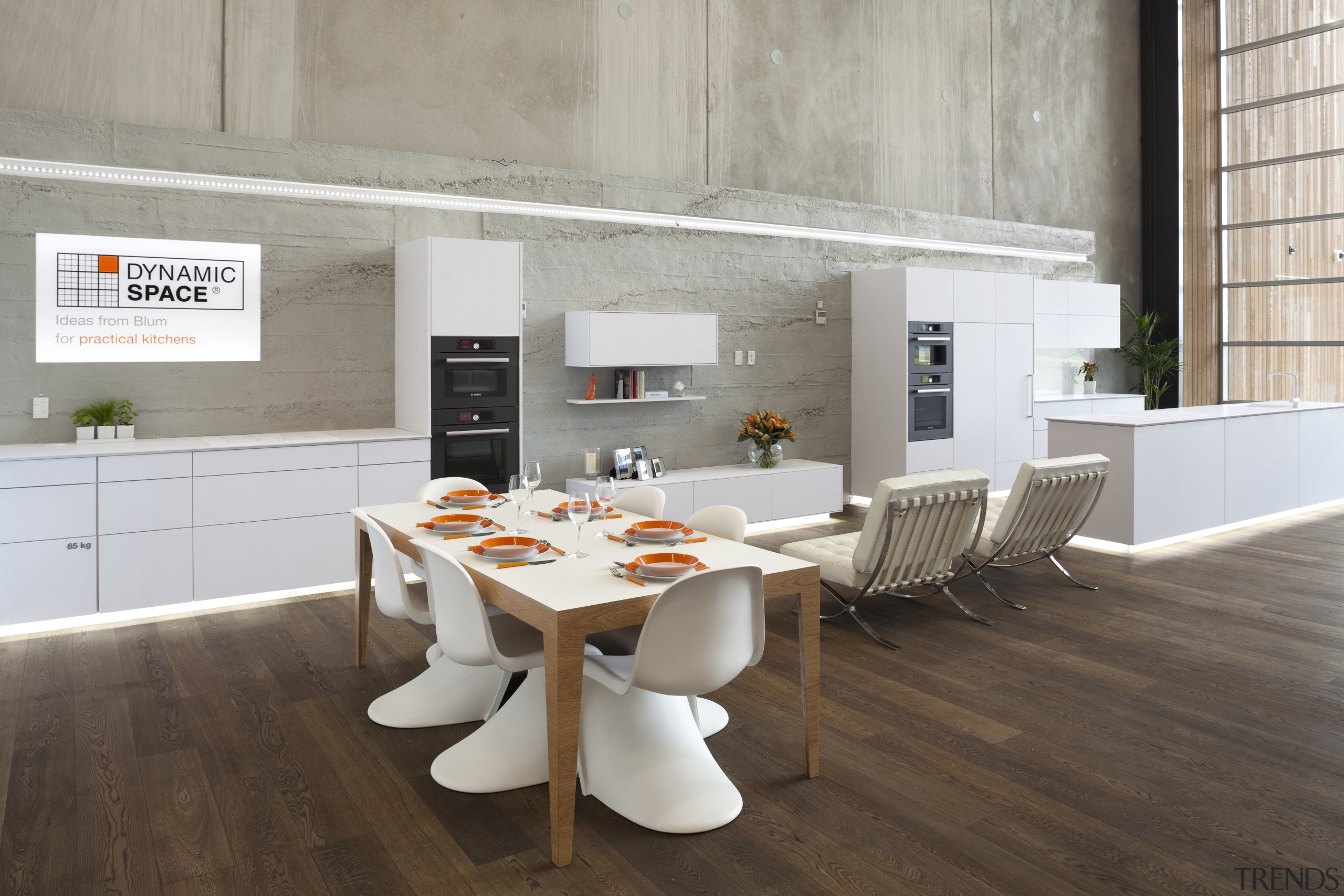 Kitchen in showroom with wooden flooring and white architecture, chair, dining room, floor, flooring, furniture, interior design, product design, table, wood, gray, brown