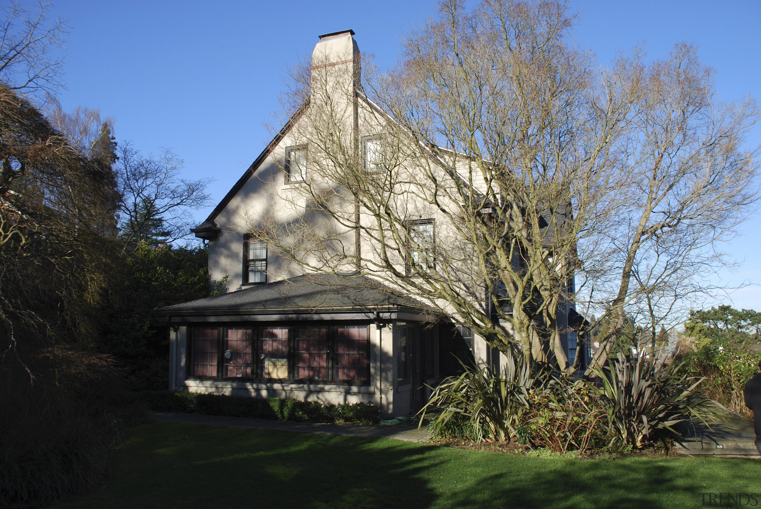 Exterior of house with chimney and trees. - building, cottage, estate, farmhouse, home, house, plant, property, real estate, roof, rural area, sky, thatching, tree, black, teal