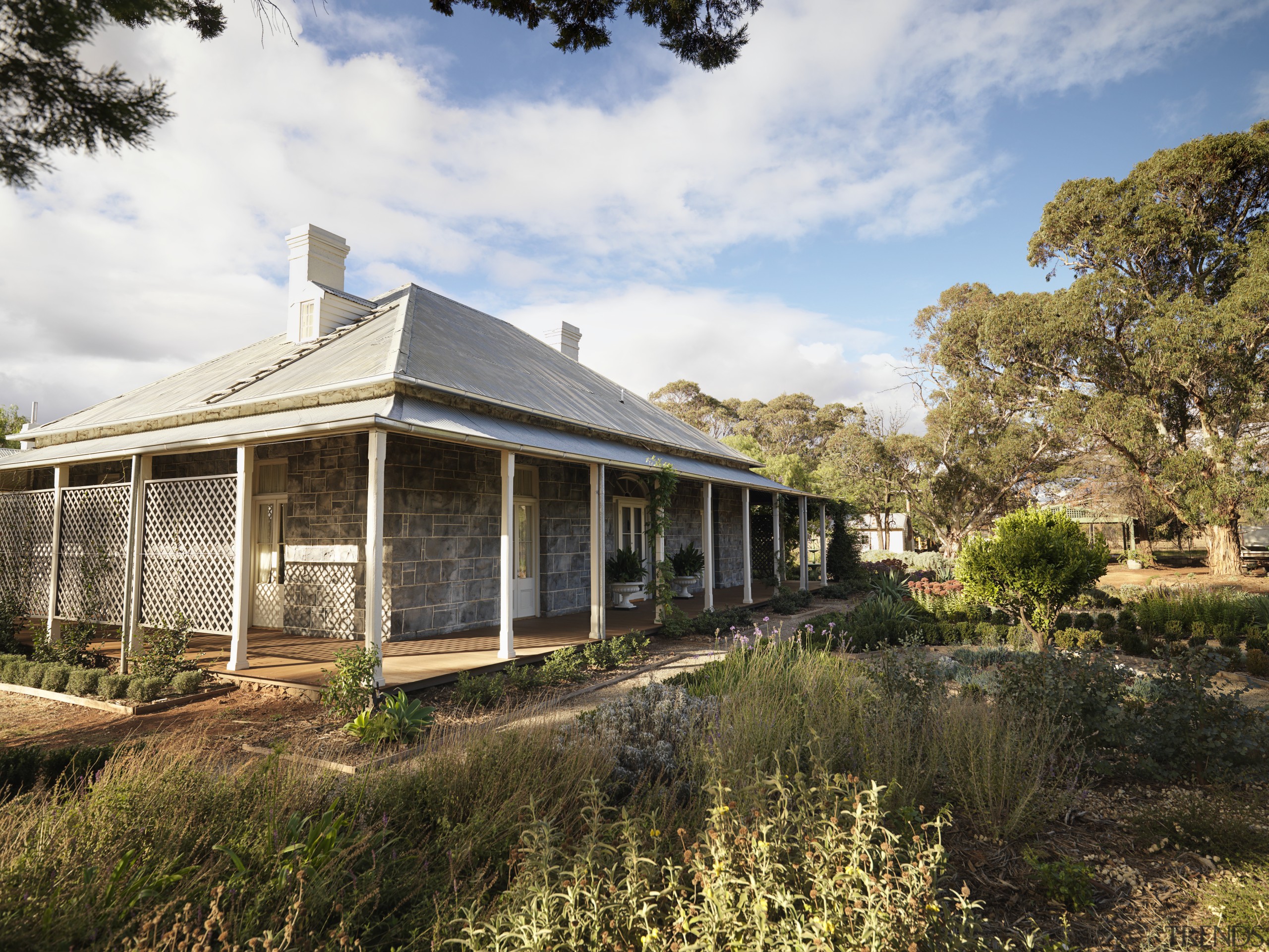 Exterior view of a colonial-styled architectural home with cottage, estate, farmhouse, home, house, landscape, plant, property, real estate, sky, tree, brown, white