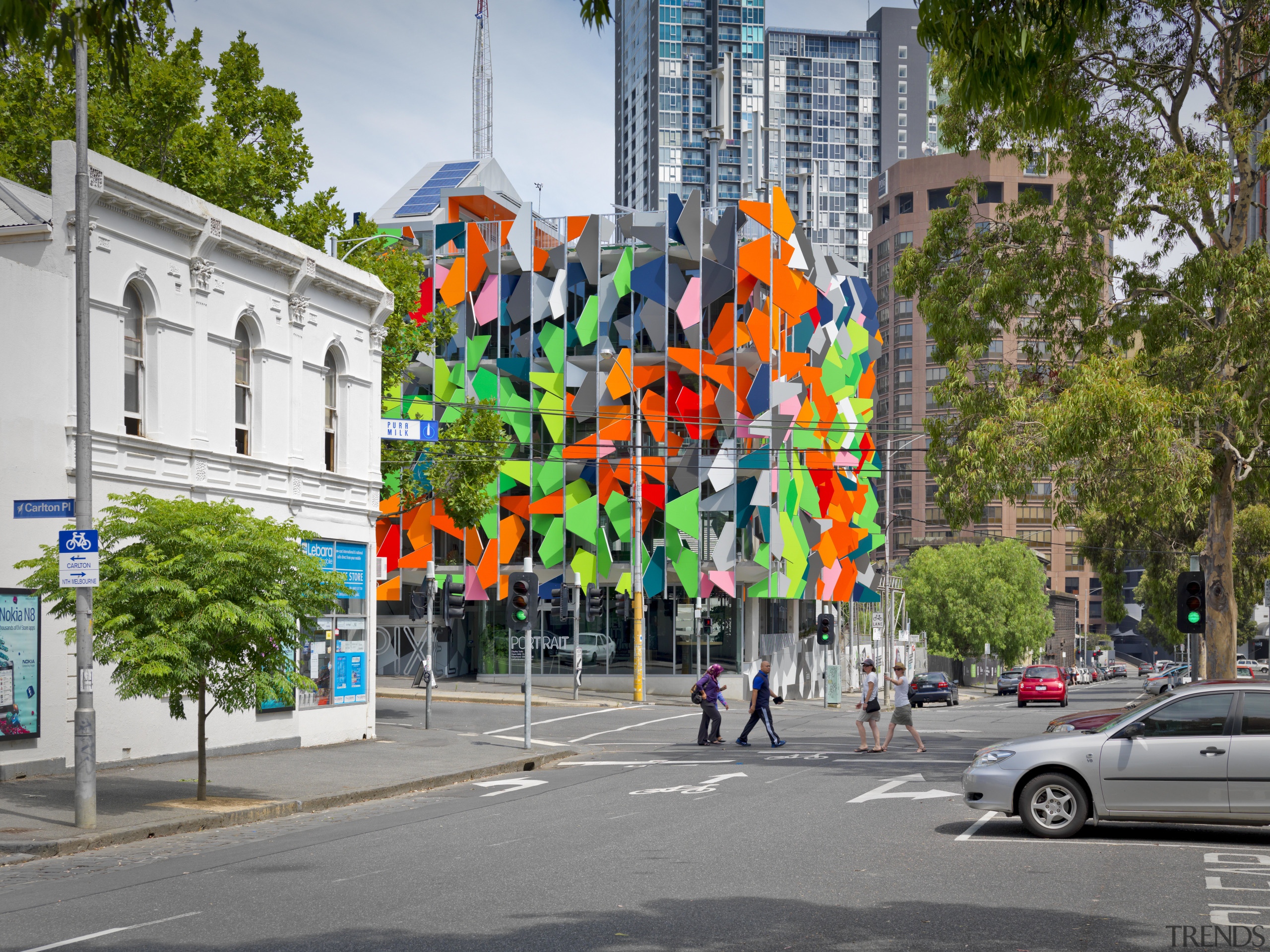 View of Pixel Building, with colorful exterior flags, advertising, city, facade, mixed use, mural, neighbourhood, road, street, tree, urban area, wall, gray