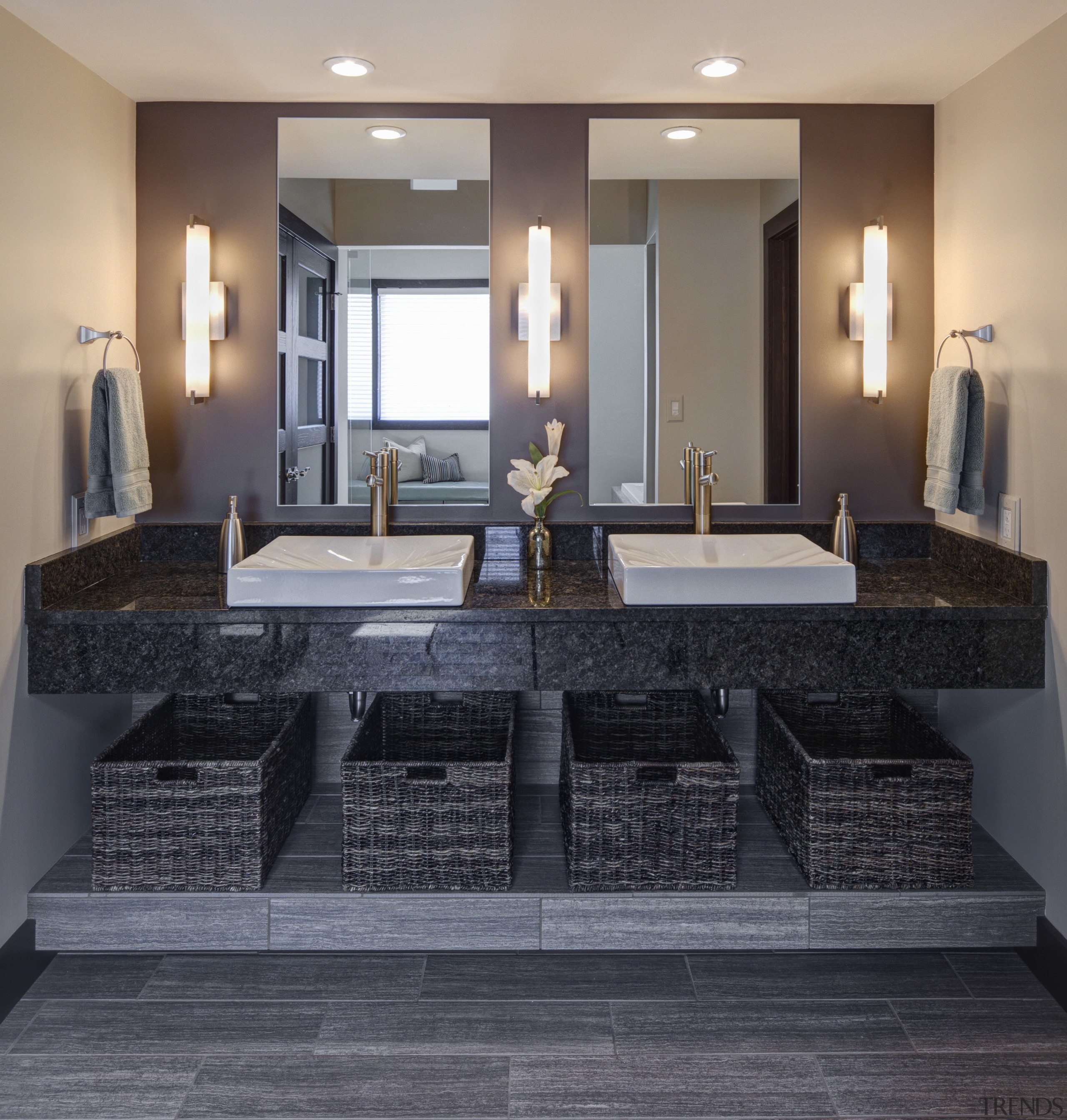 Large vanity mirrors reflect the view. The vanity countertop, floor, flooring, interior design, real estate, room, gray, black