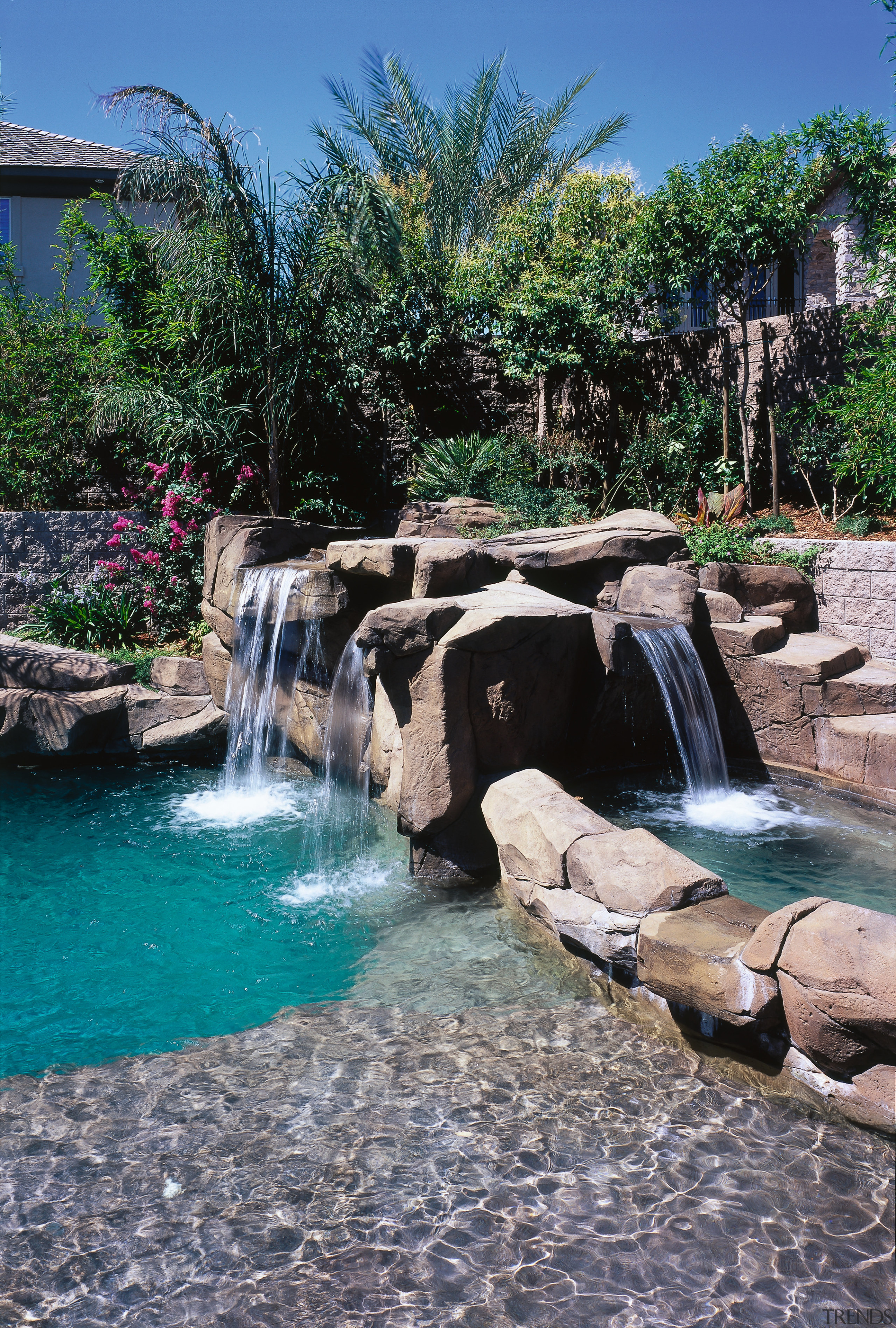 view of the pool area that includes a arecales, backyard, body of water, landscape, landscaping, leisure, pond, swimming pool, tree, water, water feature, water resources, watercourse, waterfall, gray, black