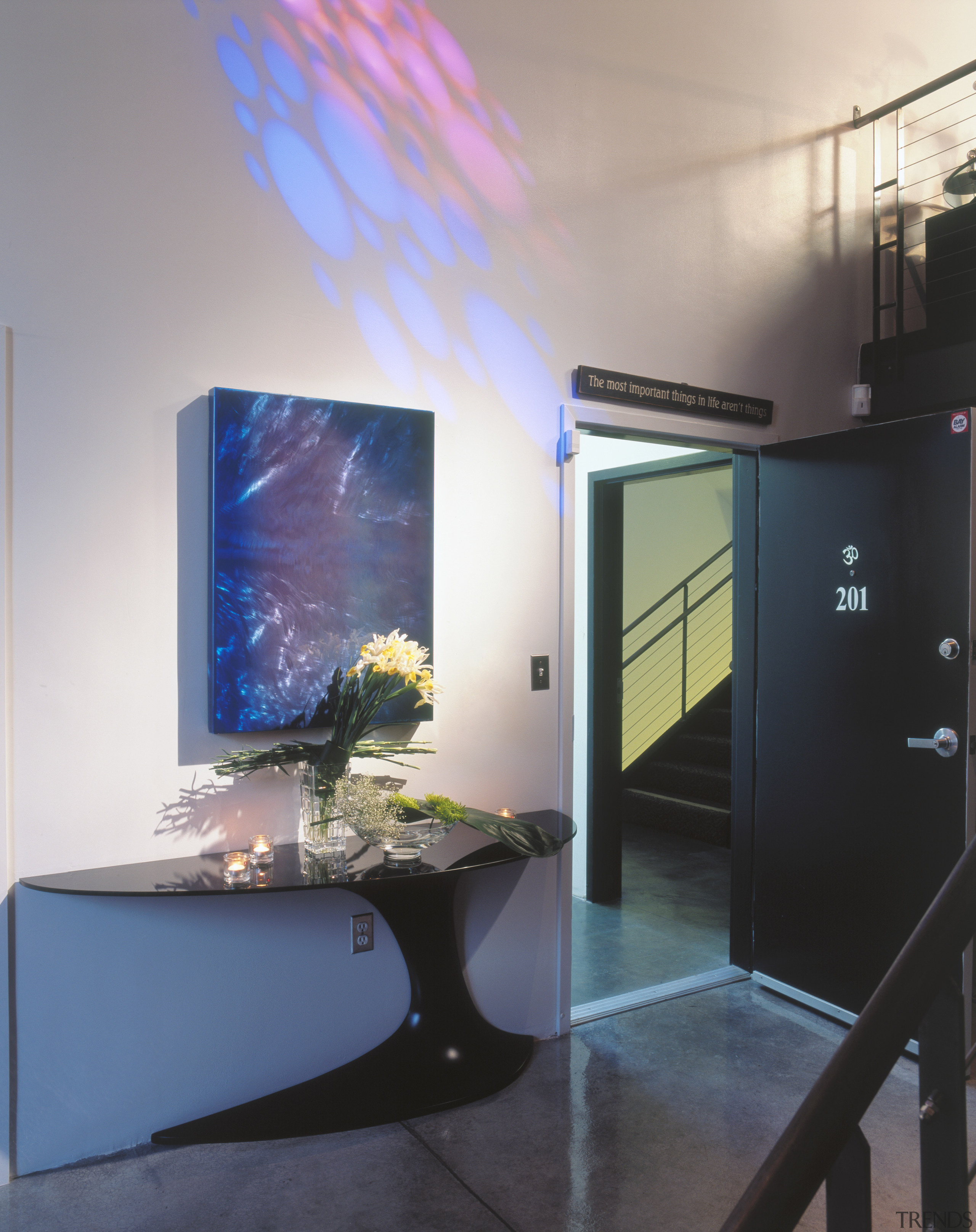 A view of the entrance way, concrete flooring, display device, glass, interior design, table, gray, black