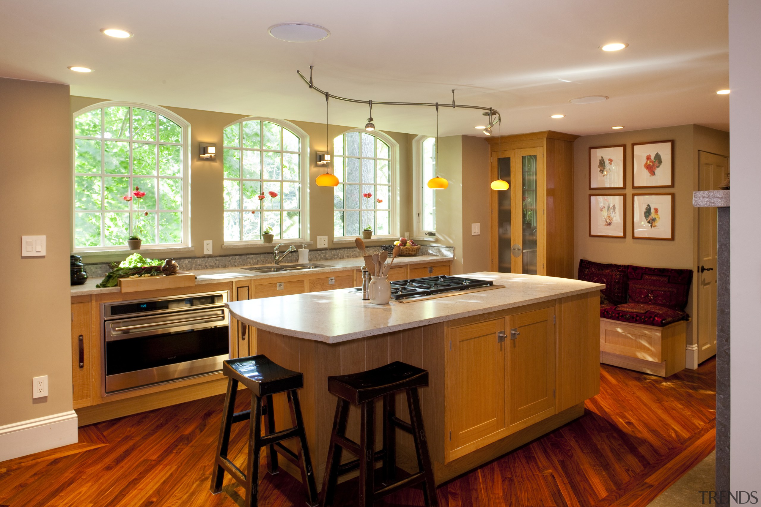 Arched windows enhance the classic appeal of this cabinetry, ceiling, countertop, floor, flooring, hardwood, home, interior design, kitchen, real estate, room, wood flooring, brown, orange