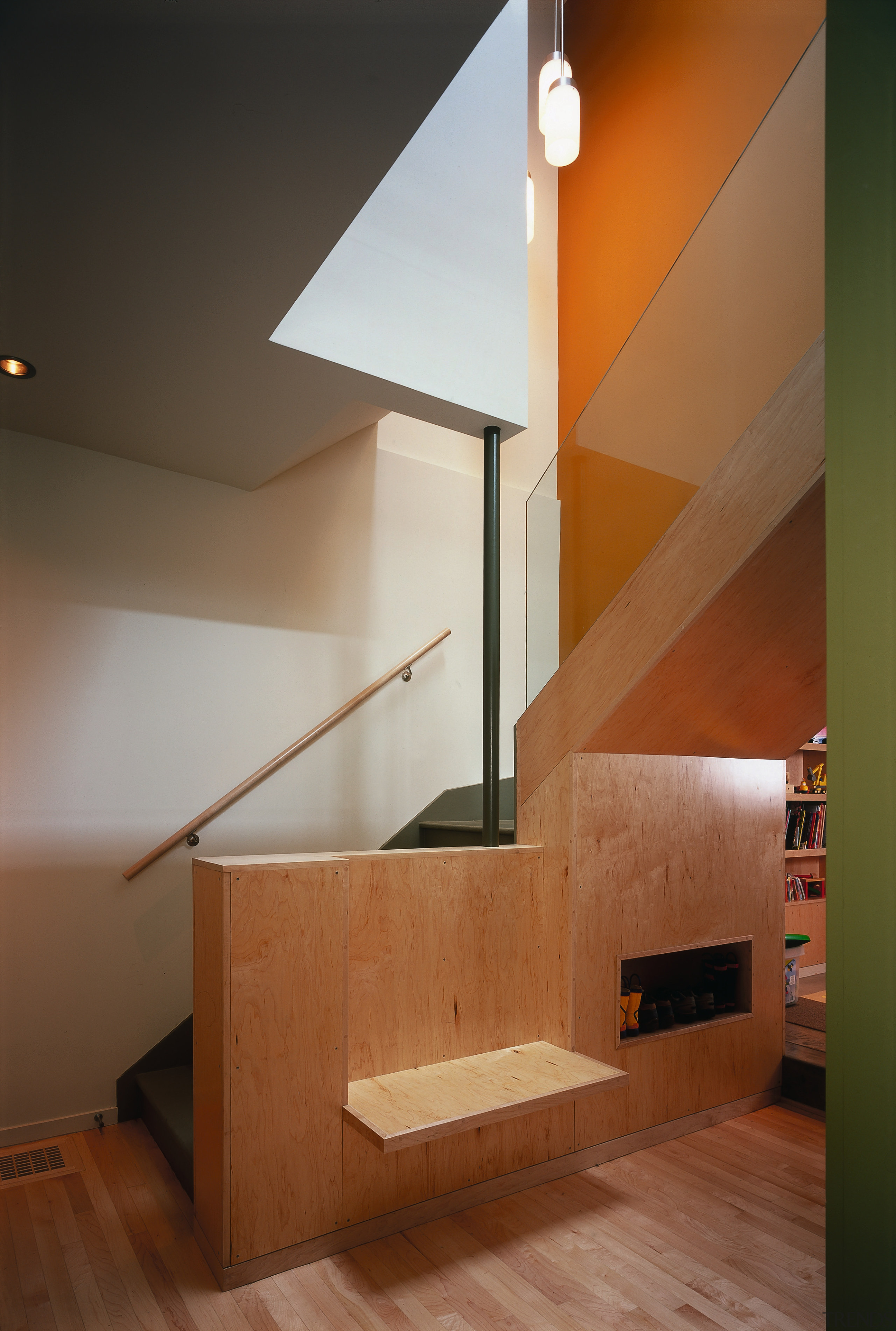 An orange wall defines the stairs leading between angle, architecture, cabinetry, ceiling, daylighting, floor, glass, handrail, hardwood, home, house, interior design, laminate flooring, lighting, loft, plywood, product design, stairs, wall, wood, wood flooring, brown