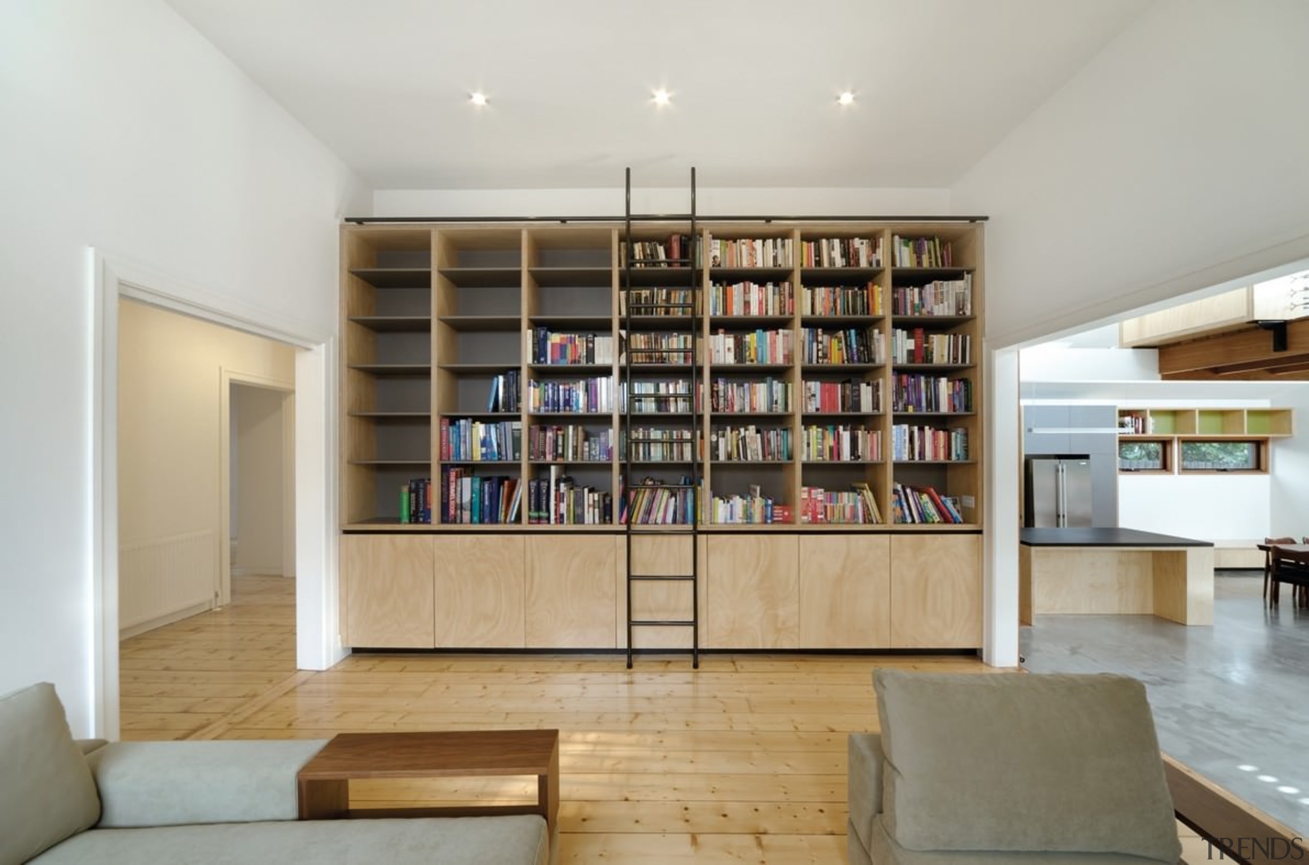 A large bookshelf separates the hallway and living bookcase, furniture, interior design, living room, property, real estate, shelf, shelving, gray