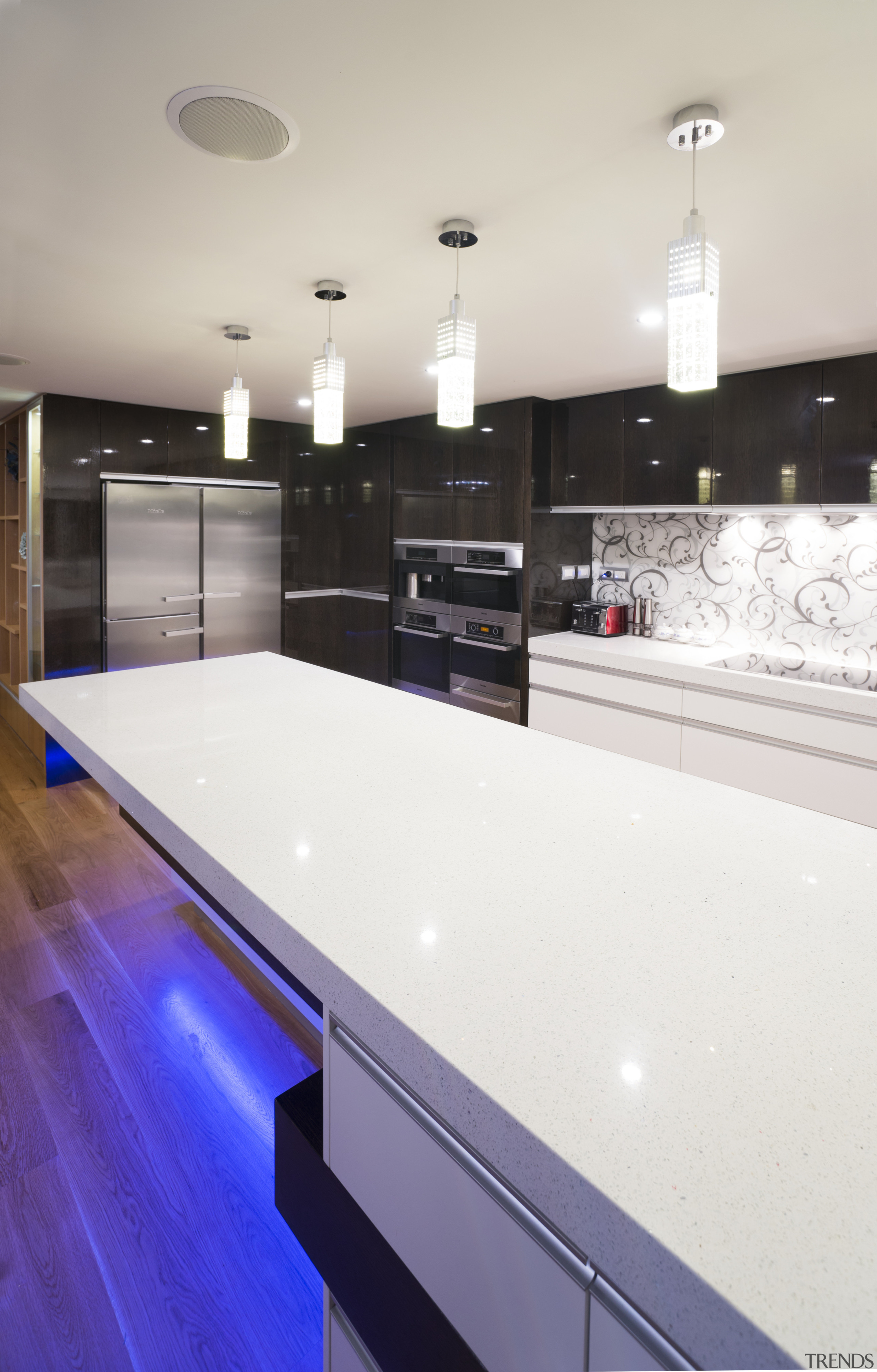 The 60mm-thick composite stone benchtop in this kitchen ceiling, countertop, floor, flooring, glass, interior design, kitchen, lighting, room, table, white
