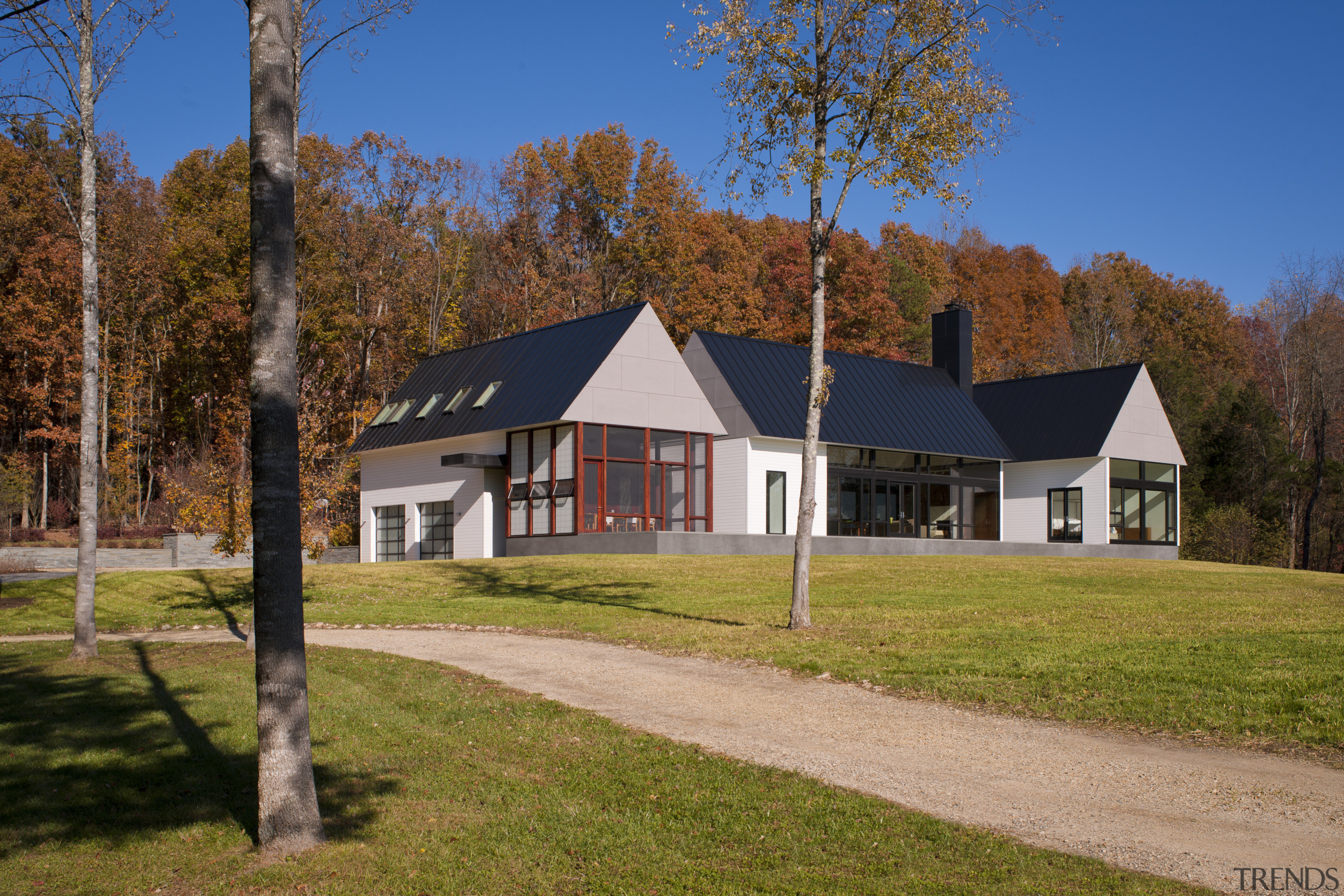 Clapboard siding and a metal roof place this barn, cottage, estate, farm, farmhouse, home, house, land lot, landscape, property, real estate, rural area, sky, tree, brown