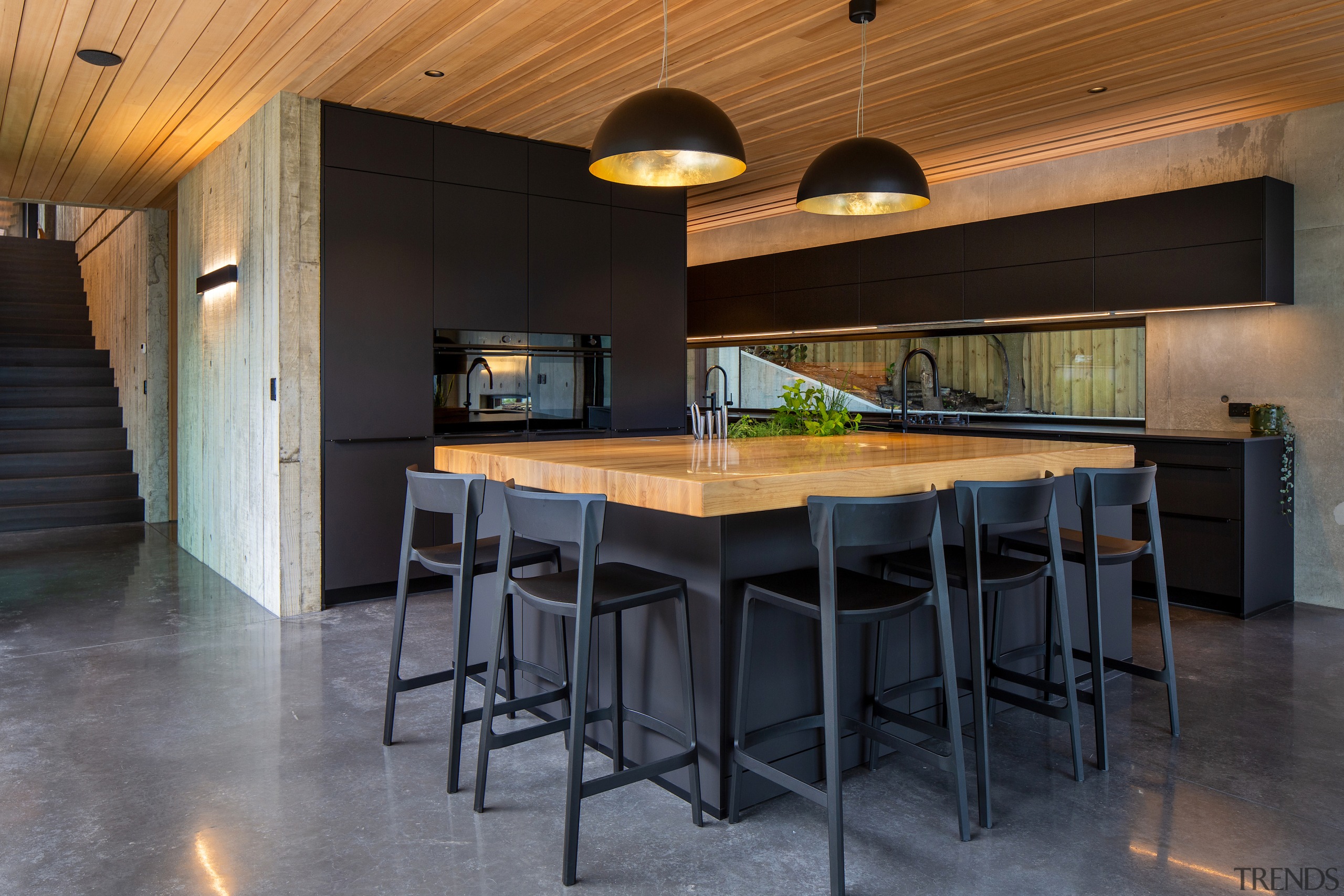 Enveloping the reflective ovens, the kitchen cabinetry has 