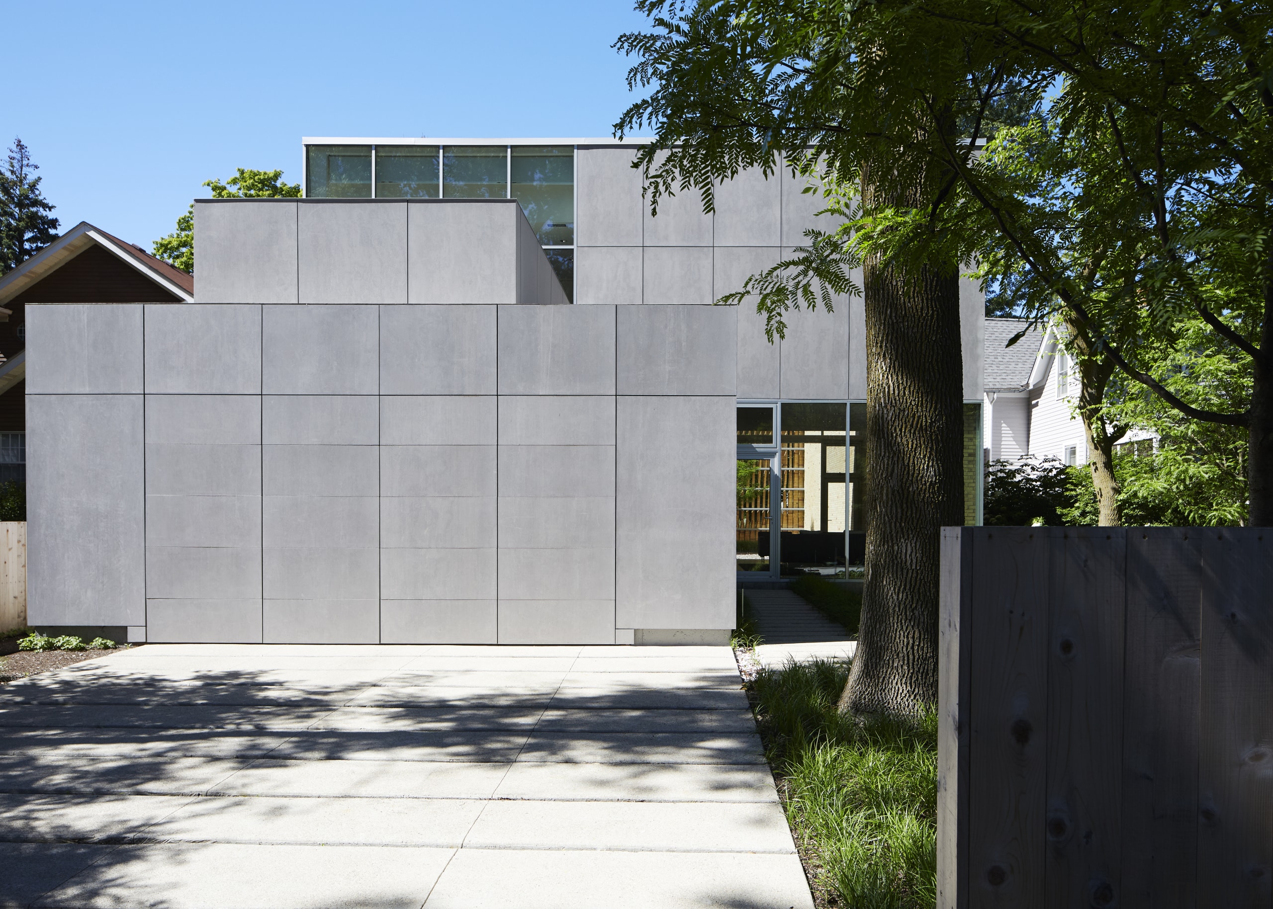 ​​​​​​​While brick encases the front and along the architecture, building, concrete, daylighting, daytime, door, facade, home, house, material property, property, real estate, residential area, room, tree, wall, gray