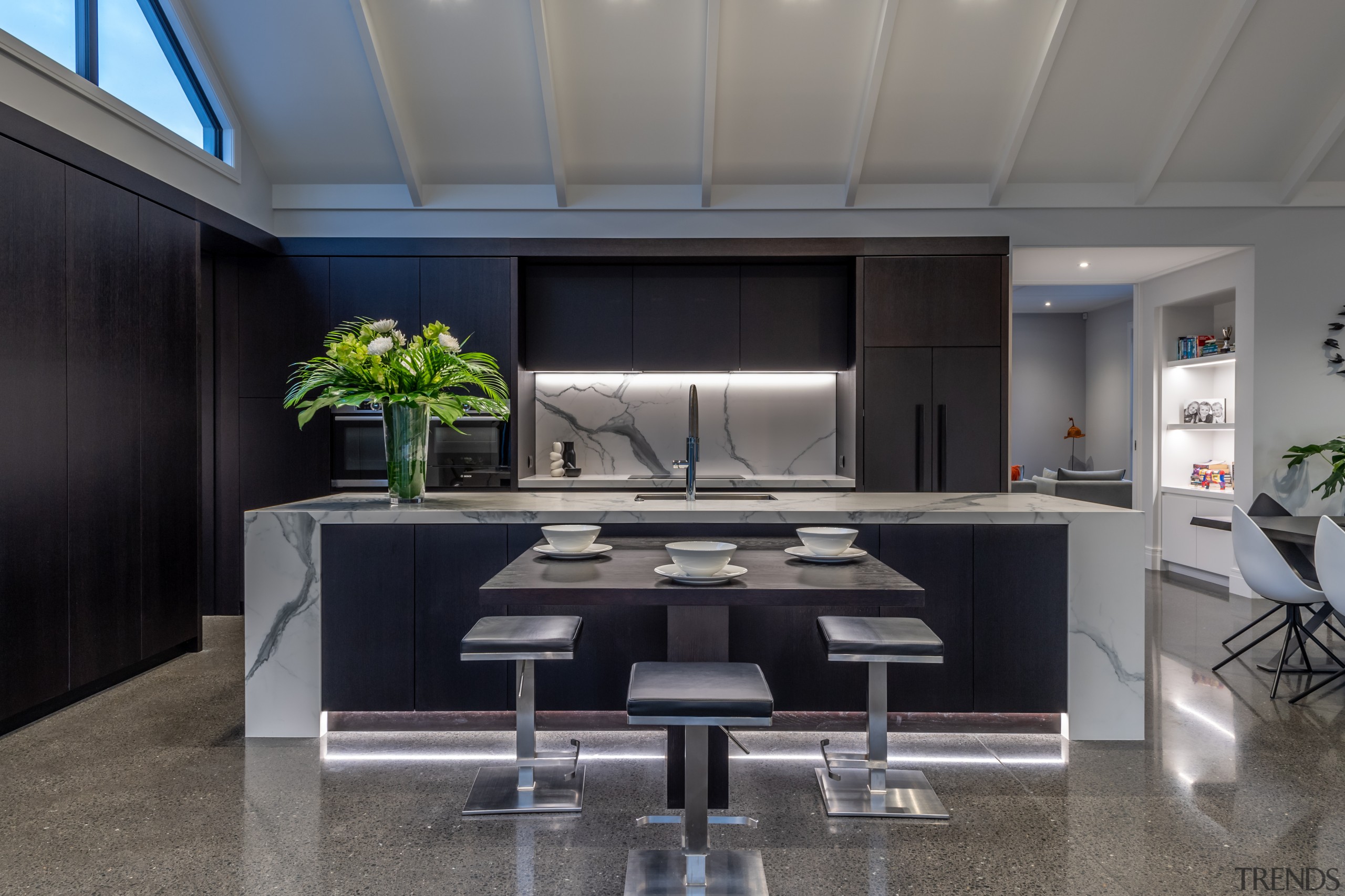 ​​​​​​​This two-tone kitchen’s pre-dominant dark cabinetry and marble-look 