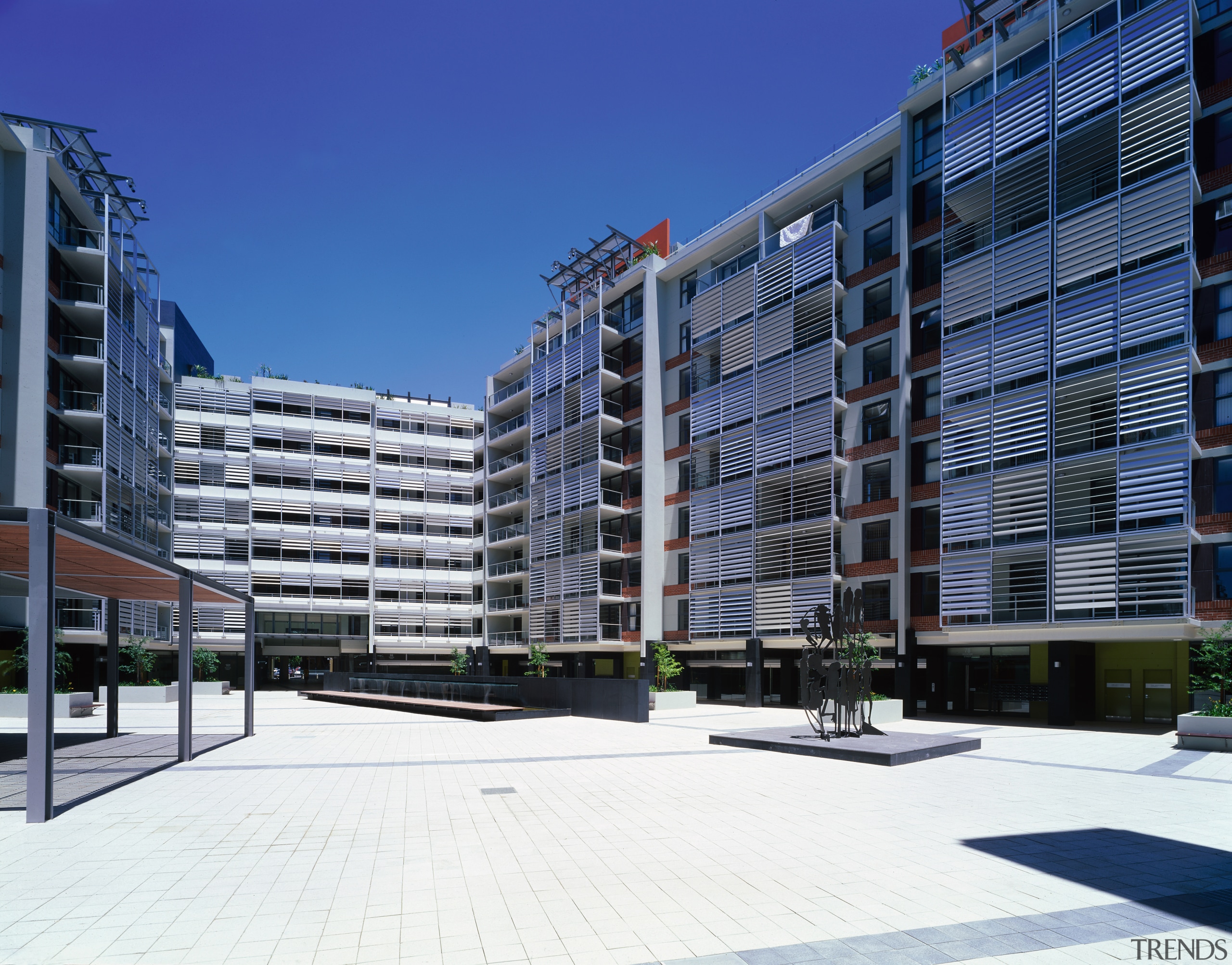 View of paved public plaza bounded by various apartment, architecture, building, city, commercial building, condominium, corporate headquarters, facade, headquarters, metropolis, metropolitan area, mixed use, neighbourhood, property, real estate, residential area, sky, tower block, urban design, blue