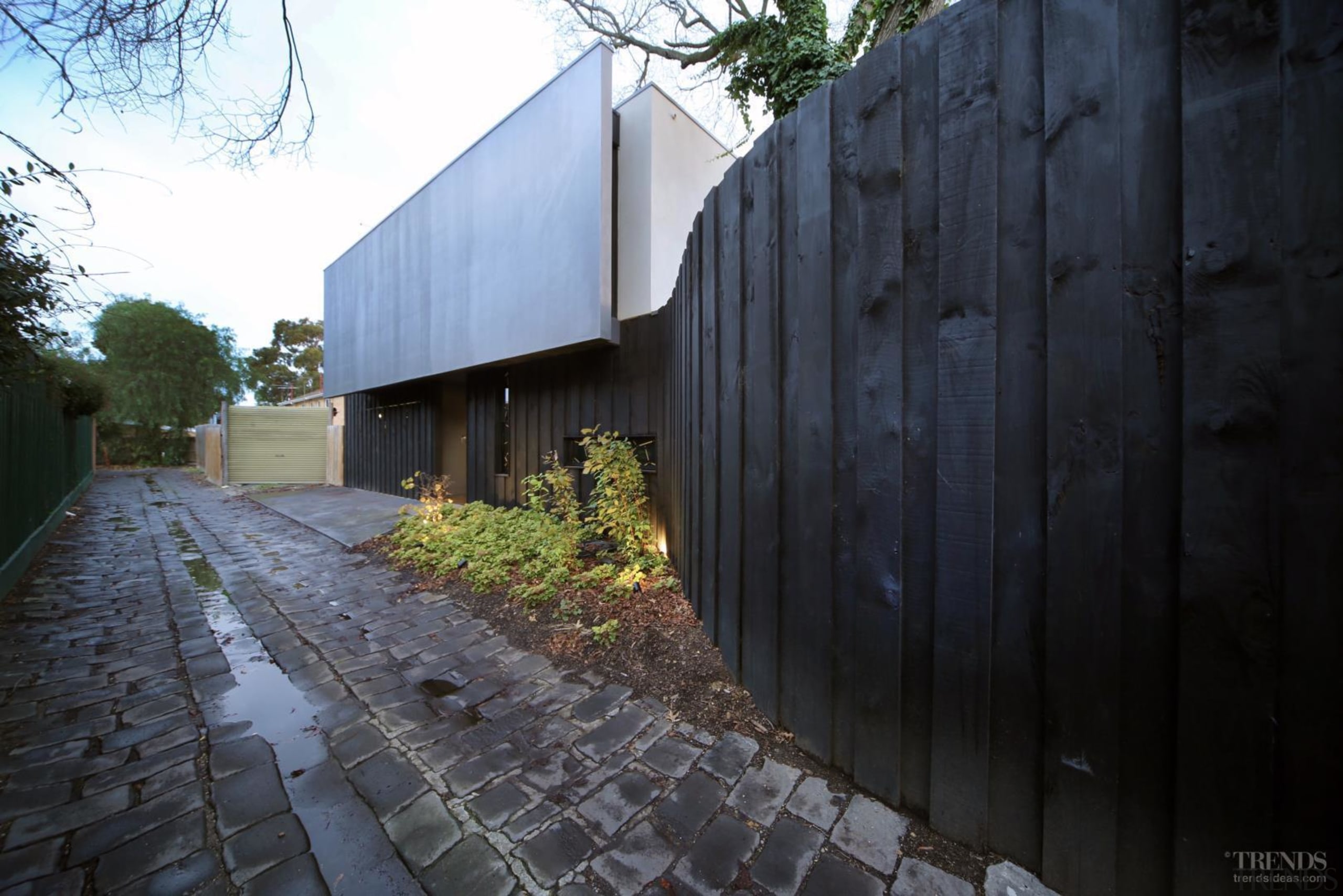 This home's hidden entry echoes the fencing along architecture, building, facade, home, house, property, real estate, residential area, sky, tree, wall, black