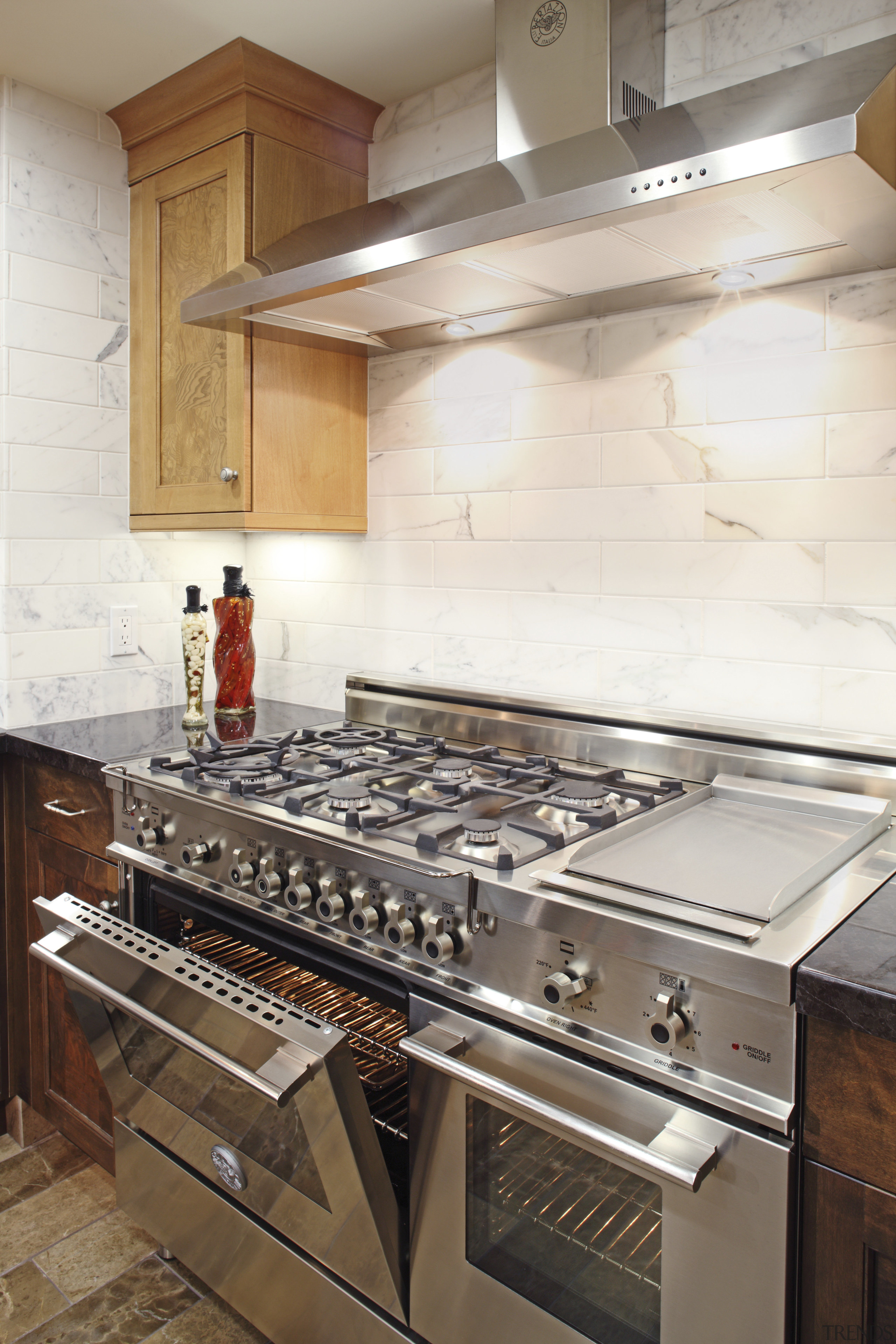 View of a contemporary kitchen which features a cabinetry, countertop, floor, flooring, home appliance, interior design, kitchen, kitchen appliance, kitchen stove, room, tile, white