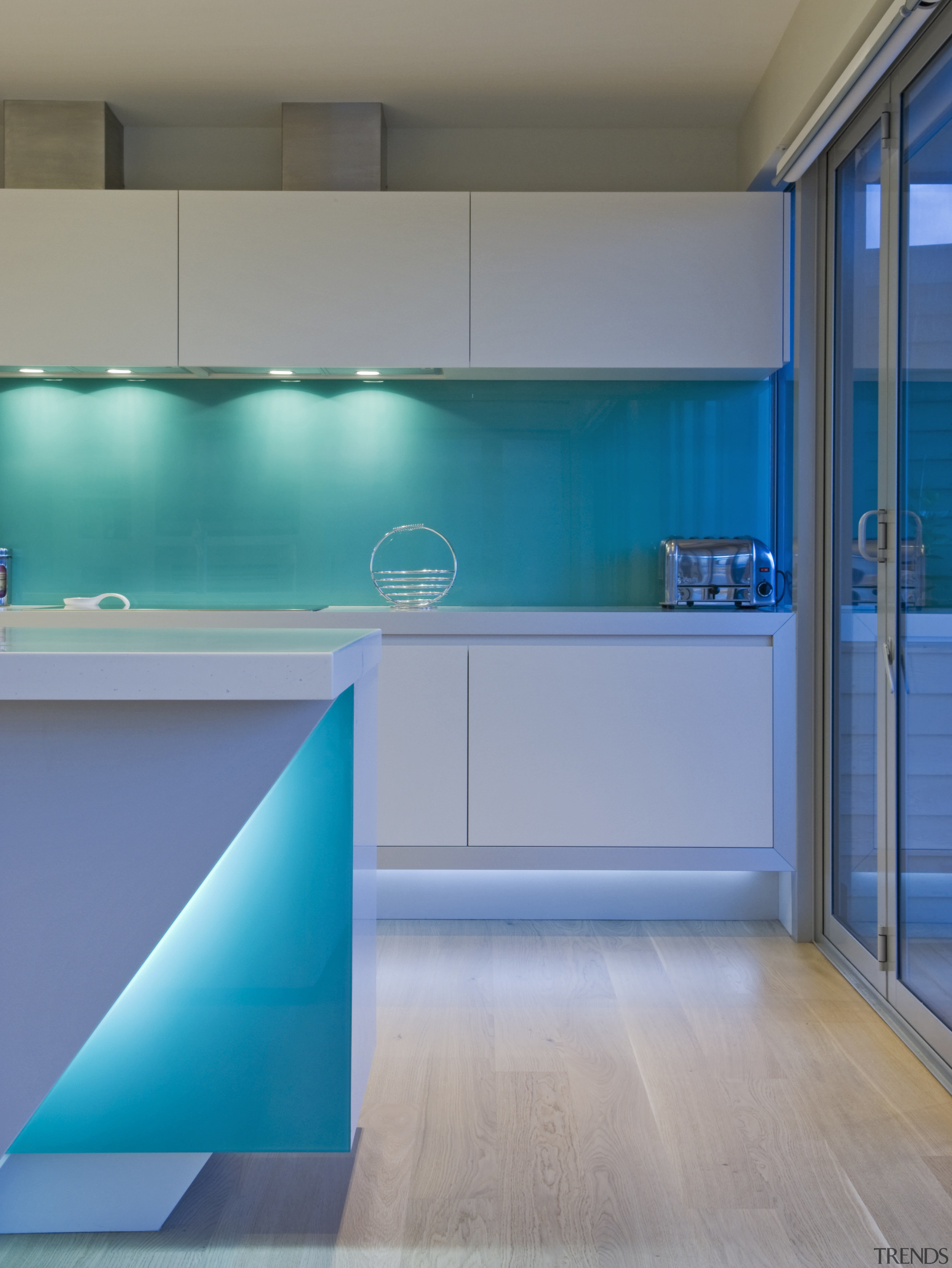 This sleek kitchen in a beach house features architecture, blue, floor, glass, house, interior design, kitchen, lighting, wall, teal, gray