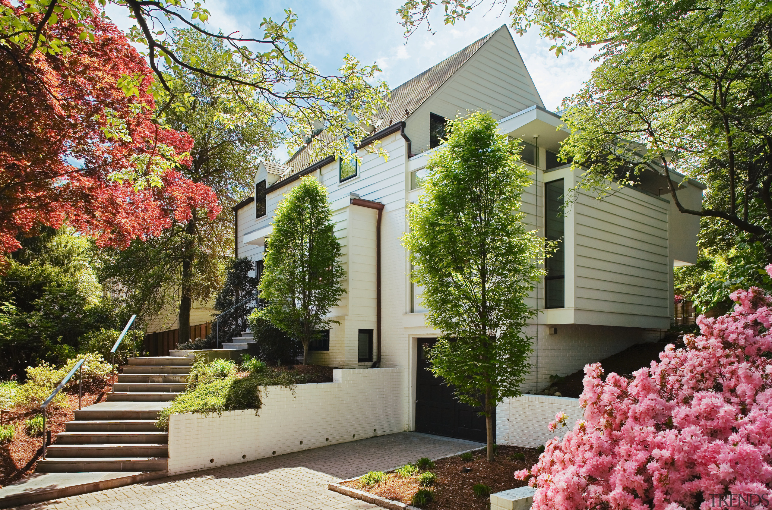 An exterior view of the entrance way to backyard, cottage, estate, facade, garden, home, house, landscaping, neighbourhood, outdoor structure, plant, property, real estate, residential area, spring, tree, yard, brown