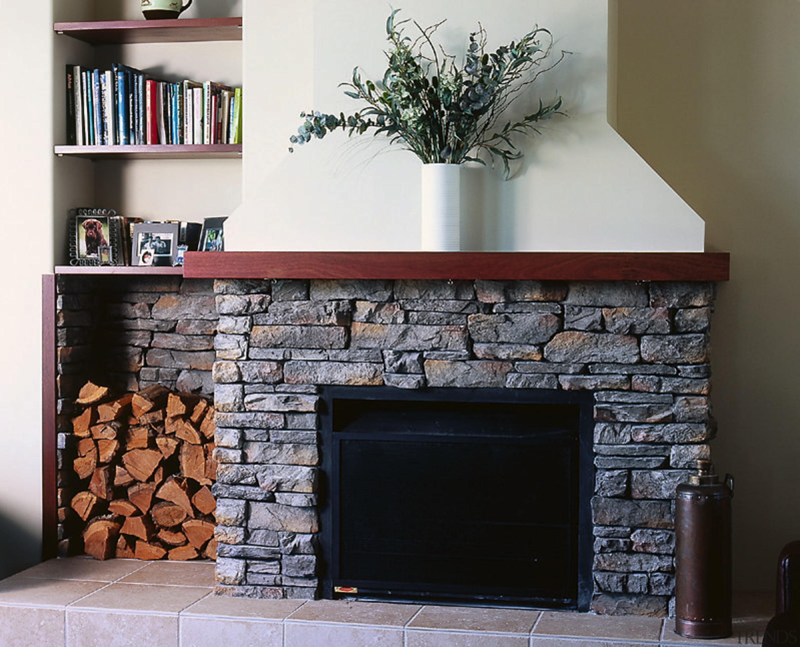 A fireplace with a stone surround. The area fireplace, hearth, wood burning stove, black, gray